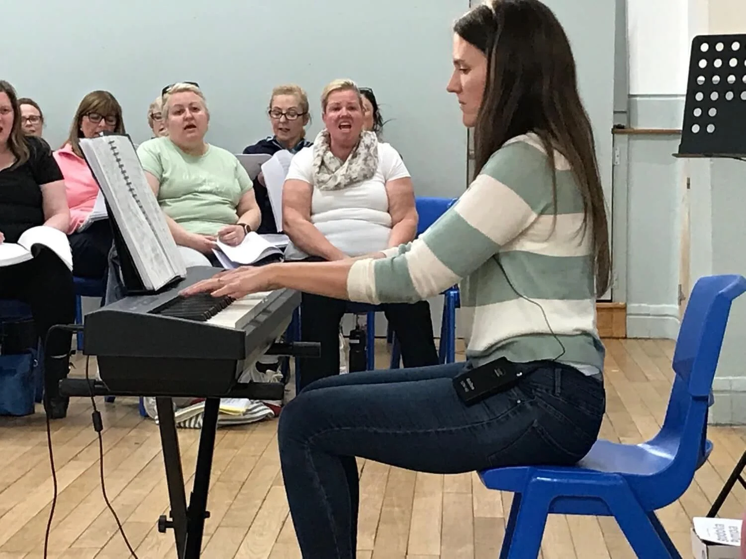 piano player playing music with several seated singers sitting in the background