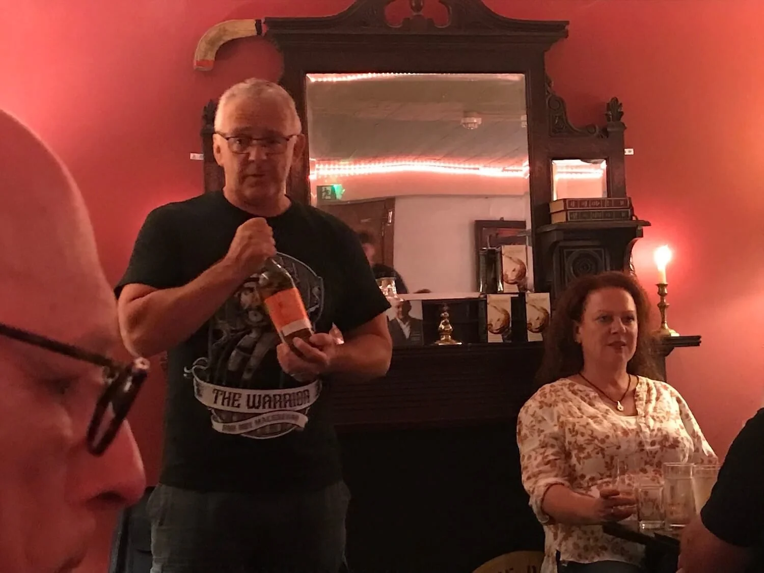 man holding a bottle of Scottish whiskey in a room with red walls