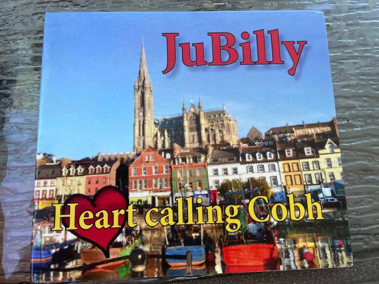 JuBilly CD cover with blue sky and Irish buildings entitled "Heart calling Cobh"