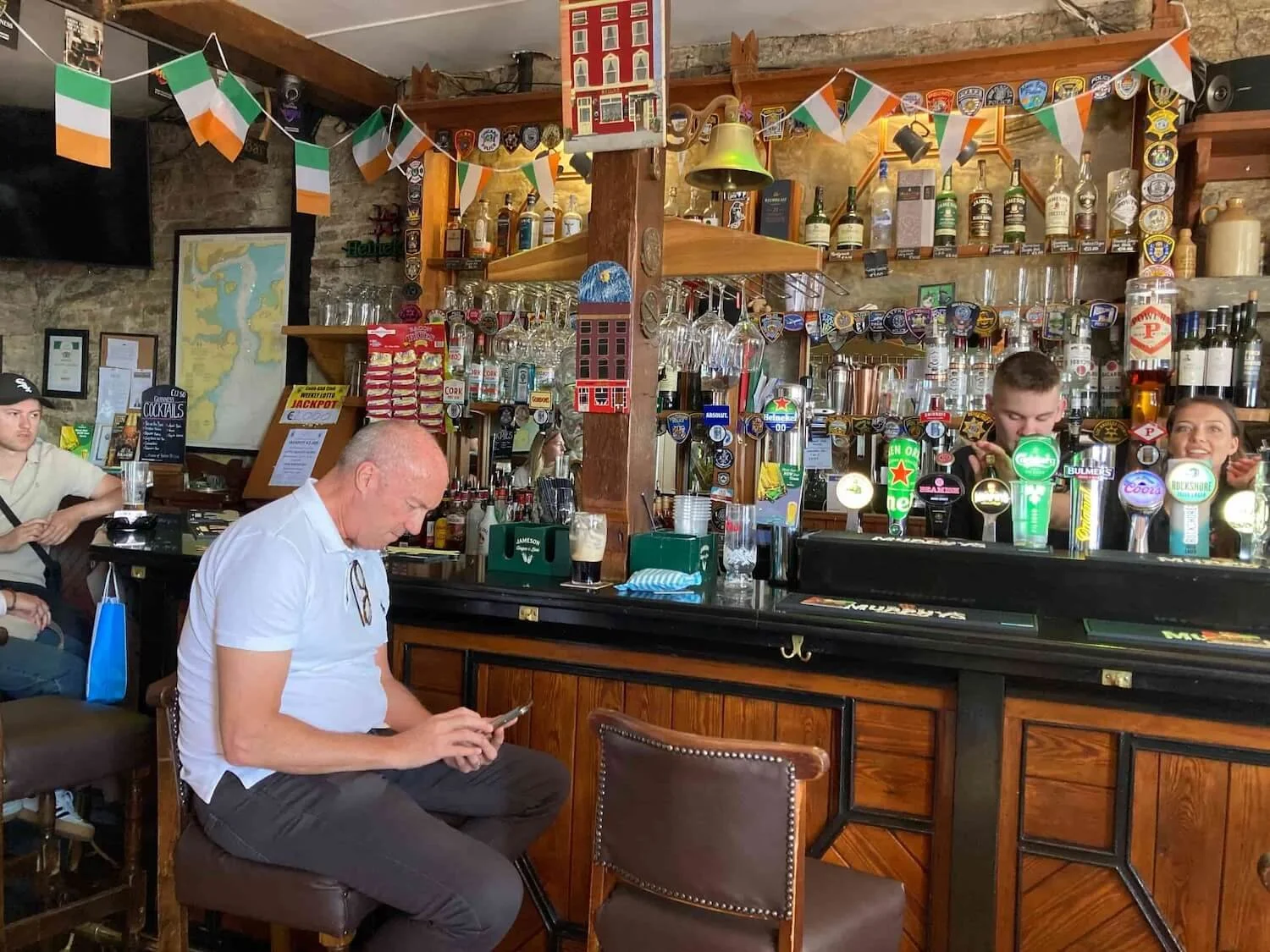 man sitting at an irish pub bar looking at his phone