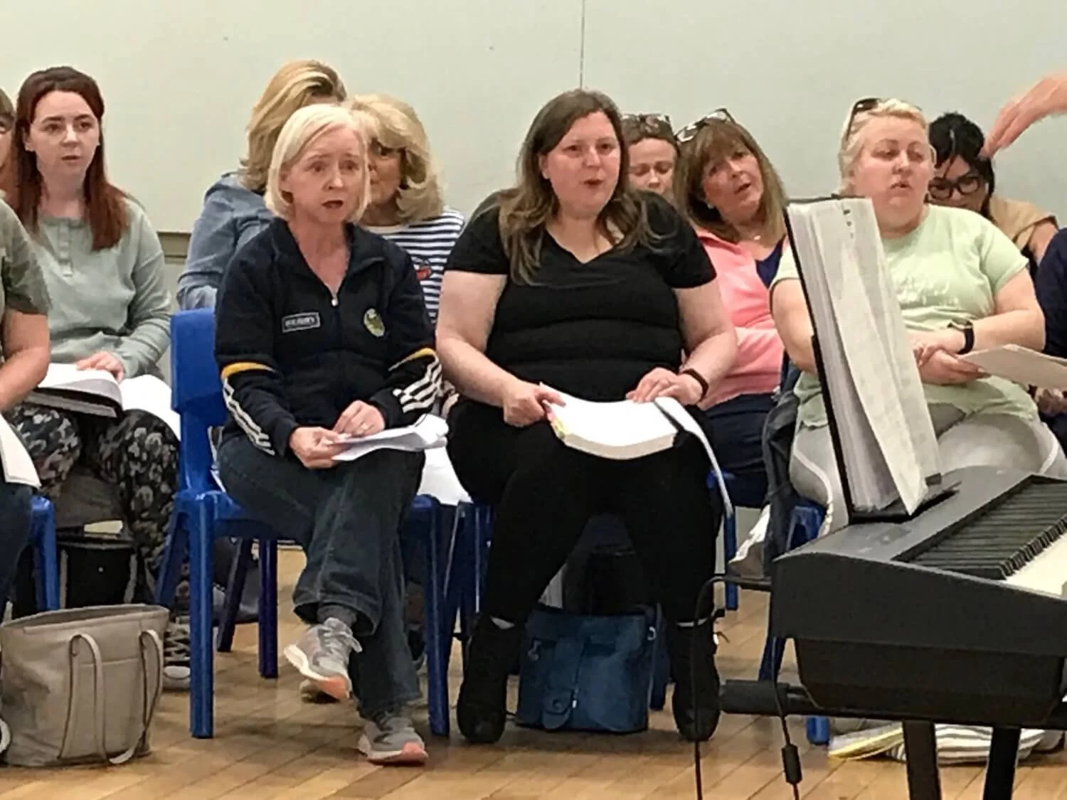 seated choir singers singing while holding sheet music