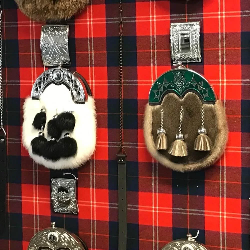 two Scottish sporns displayed on black and red tartan fabric