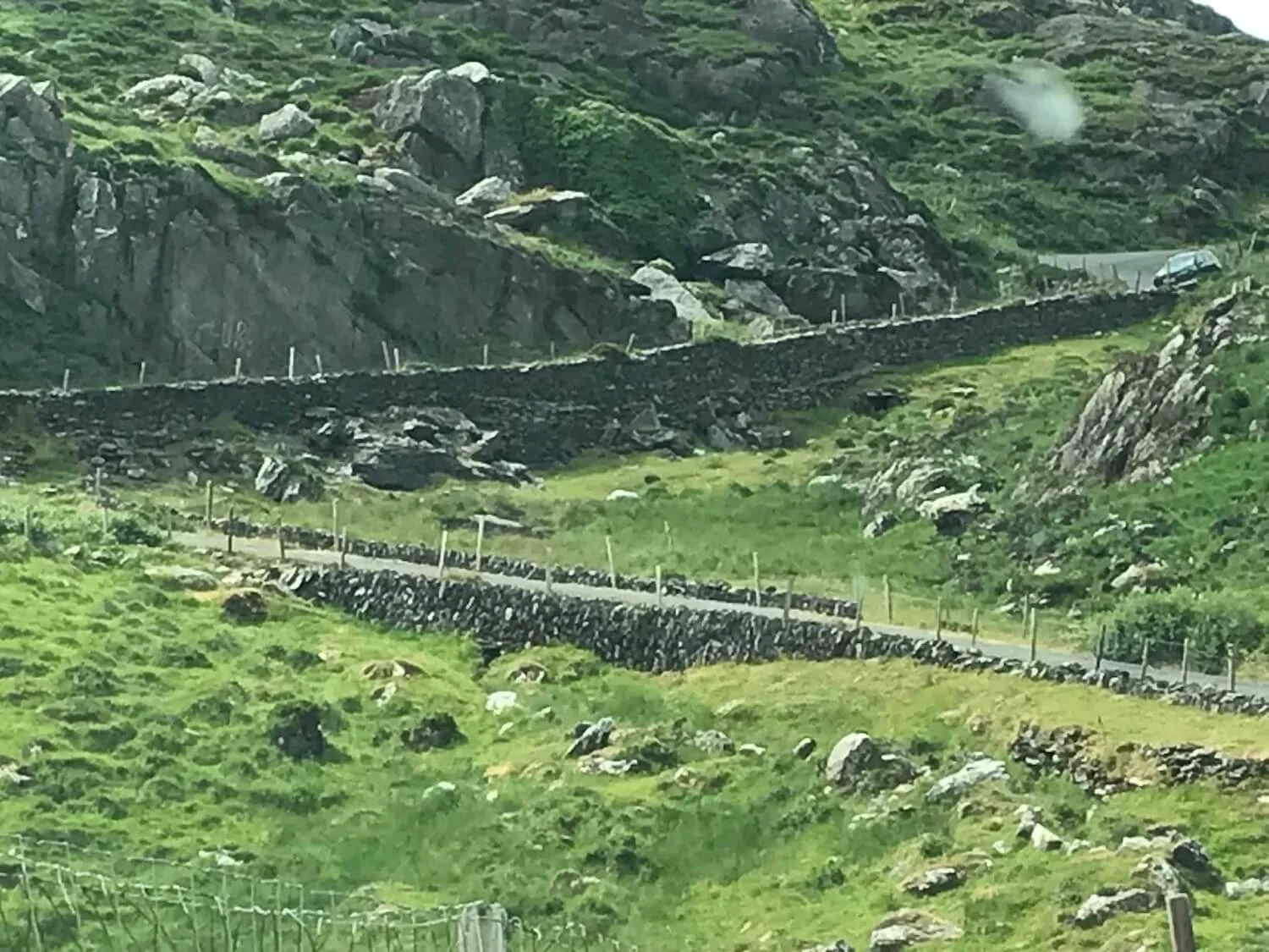 a road made of stone winding up a green hillside