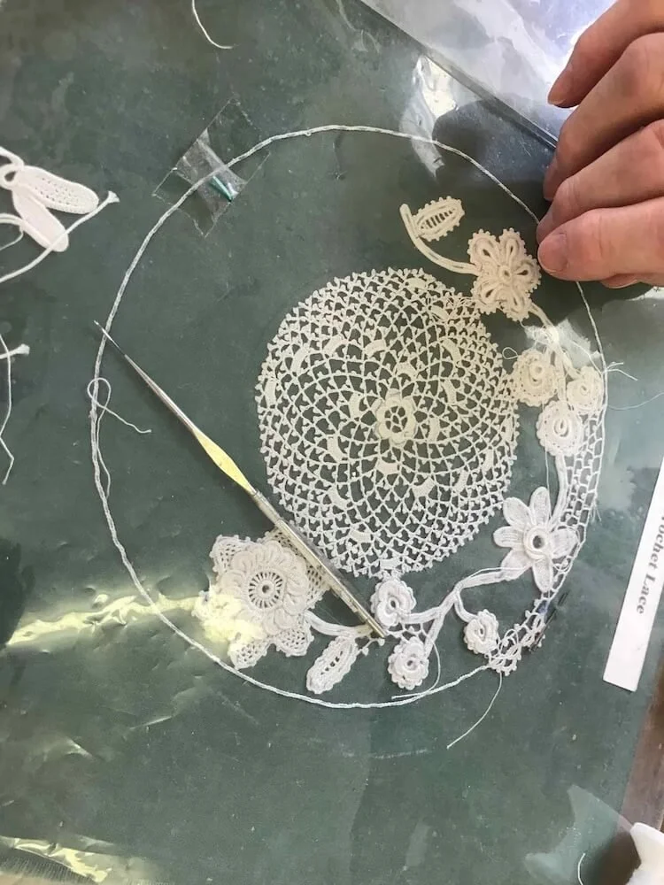 a lace project with flowers in progress including the crochet needle