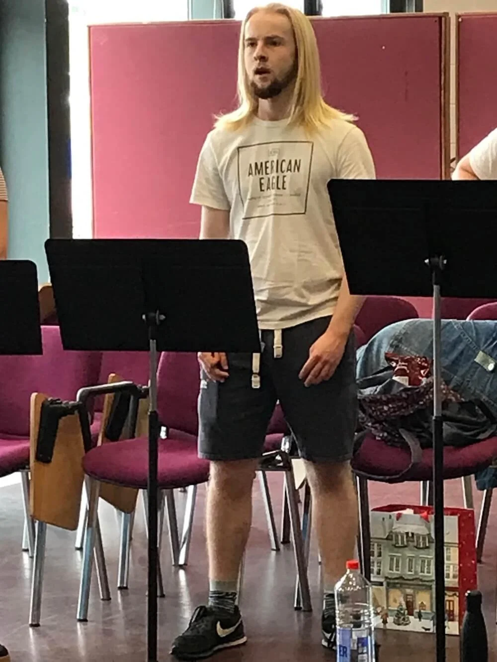 man singing while standing behind a music stand