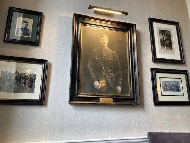 historical framed photographs hanging on a gray wall under an art display lamp