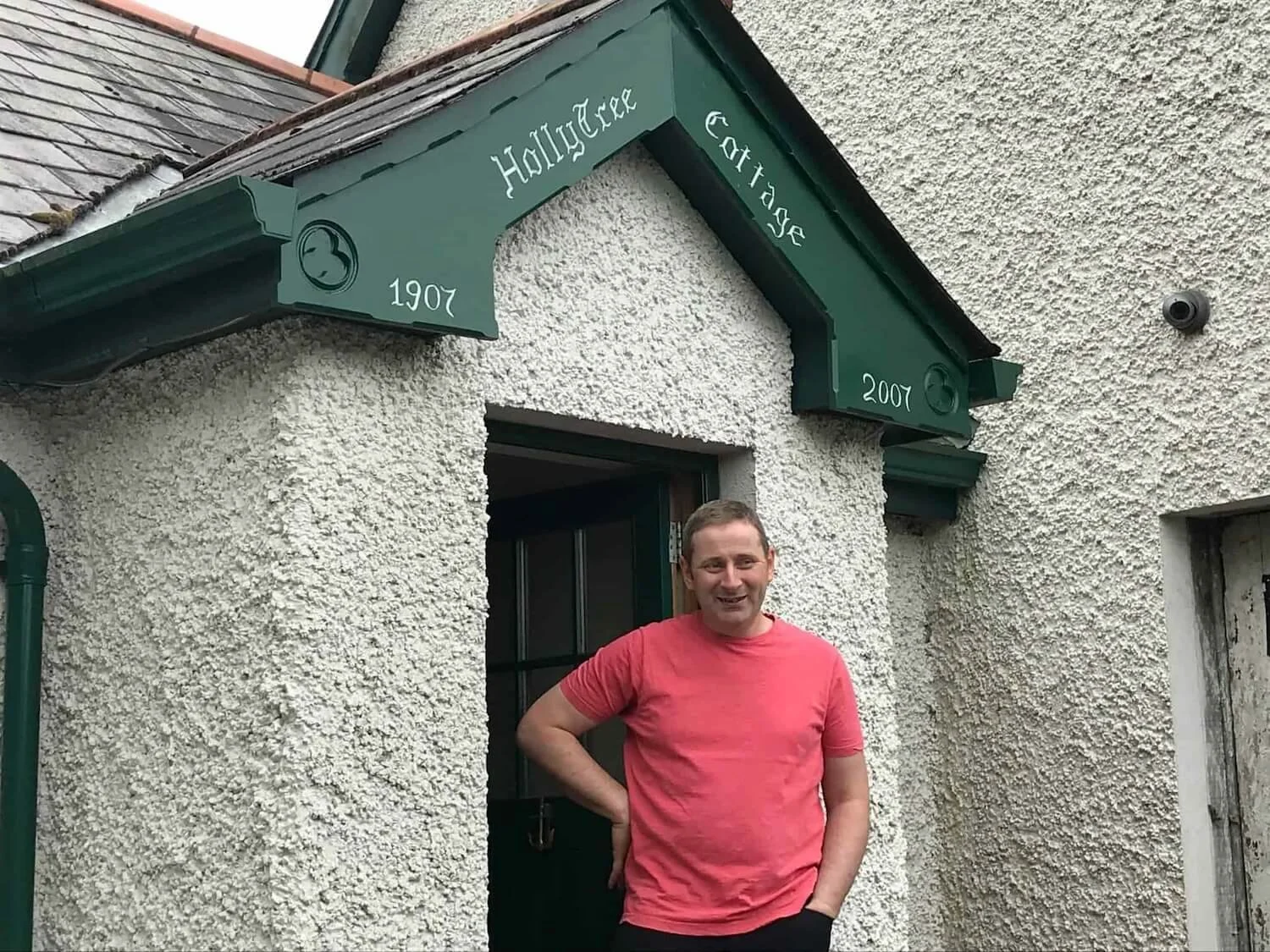 man in salmon colored shirt standing in front of the entrance to HollyTree Cottage.