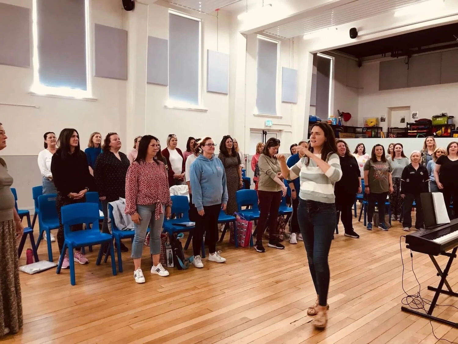 large group of singers standing in an auditorium waiting during a rehersal