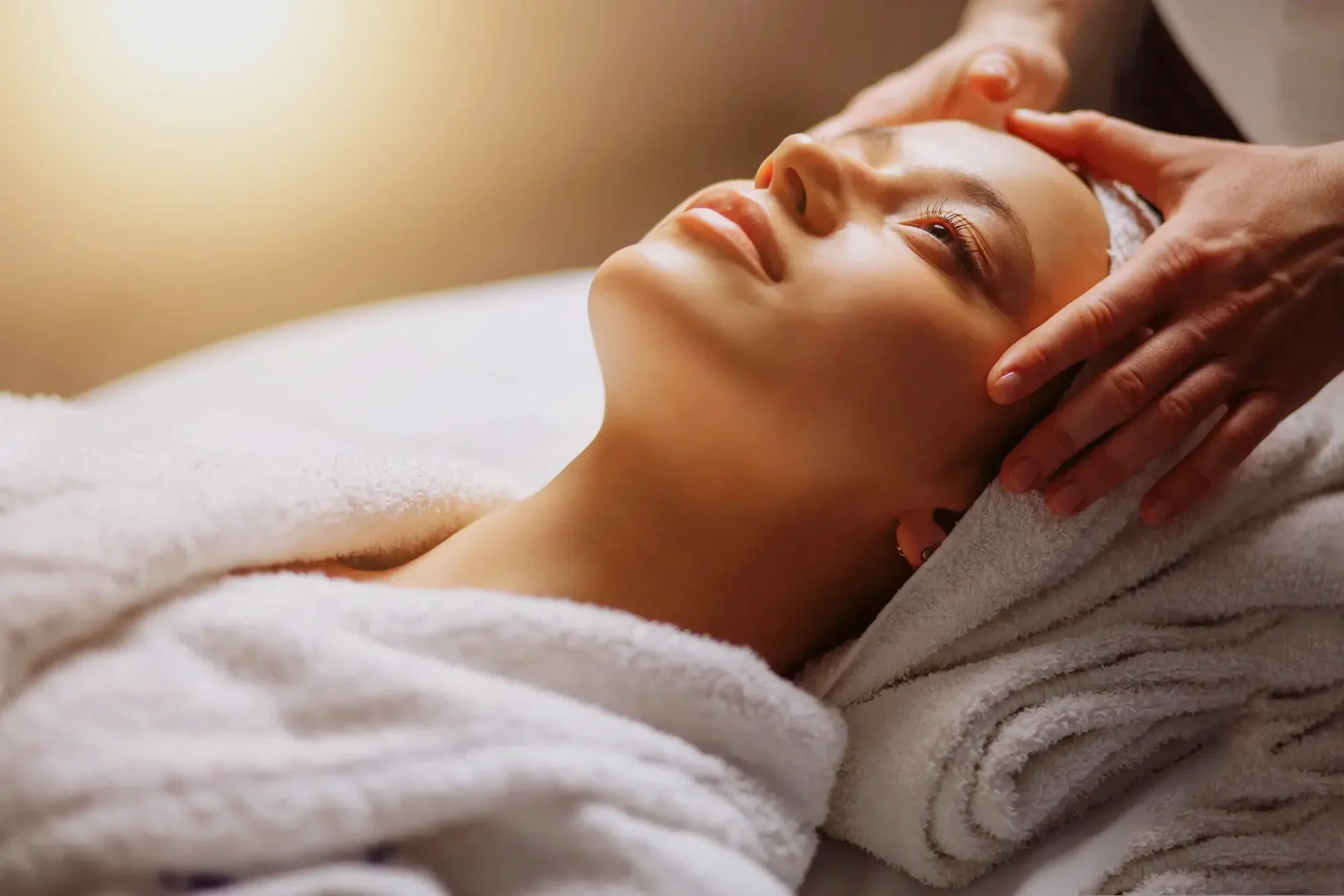 A woman receiving a massage while lying on a massage table with her head resting on a towel