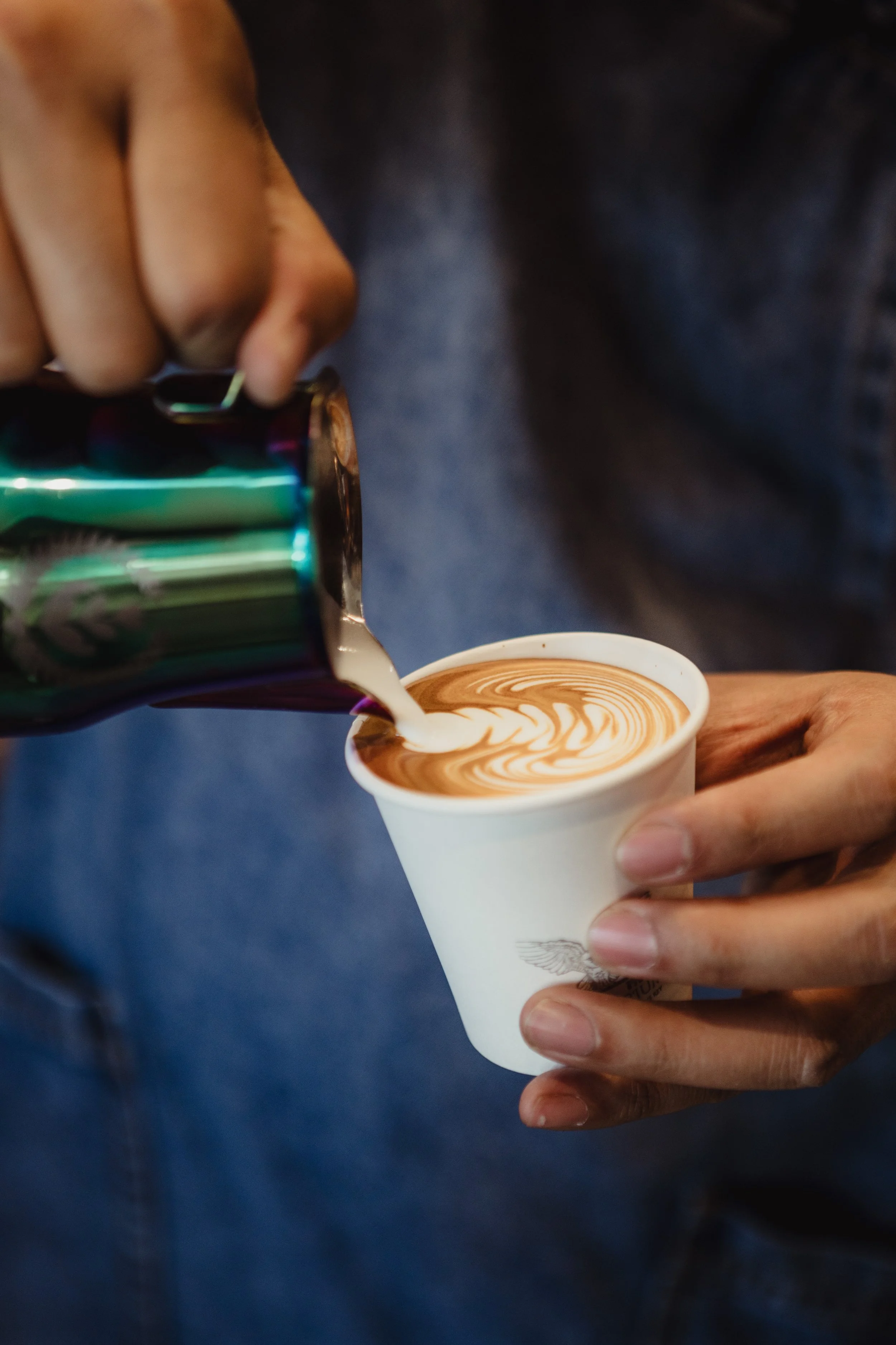 Steamed milk is being poured into a latte to make art 