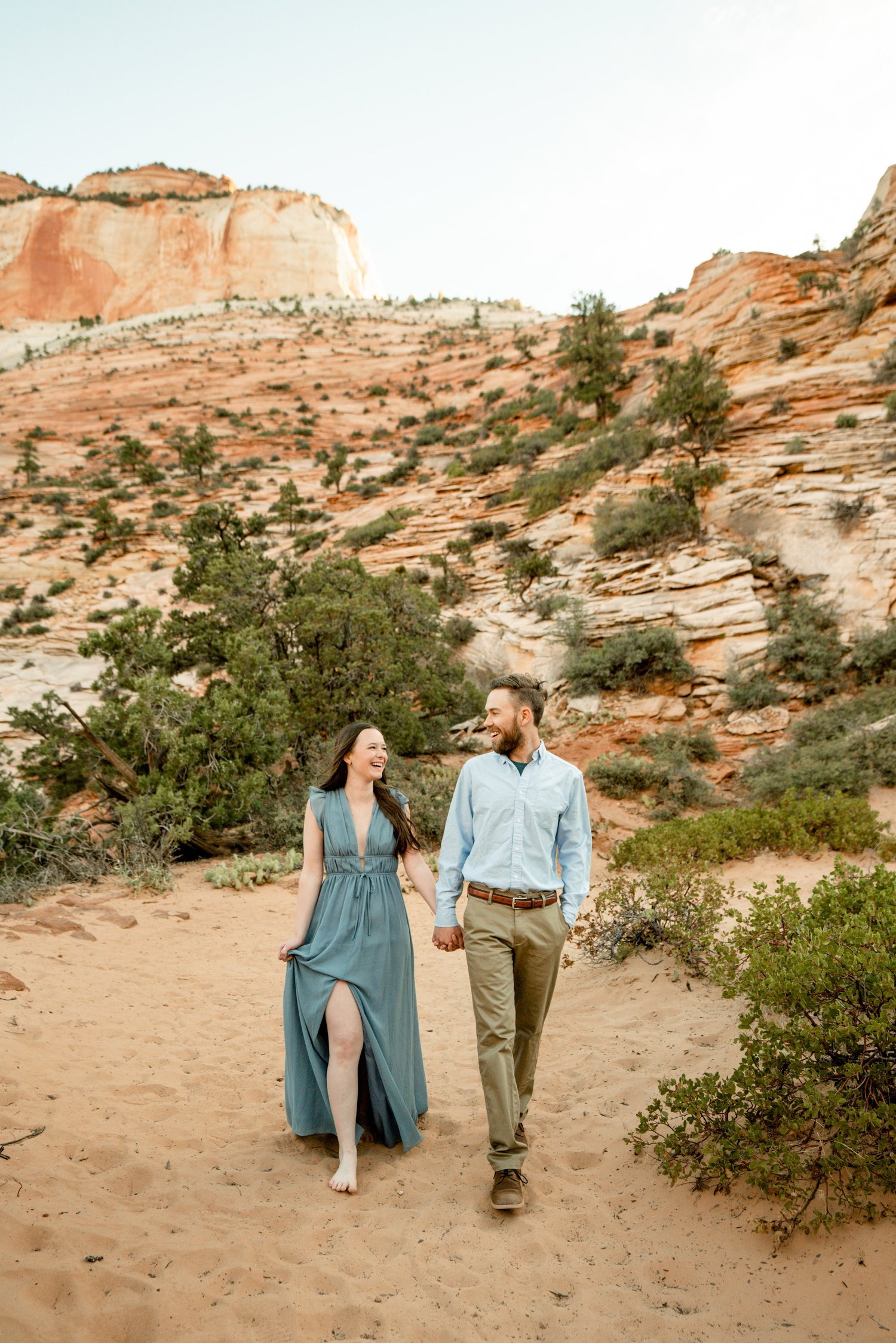 Cody and Leslie walking on a sandy trail in a desert landscape.