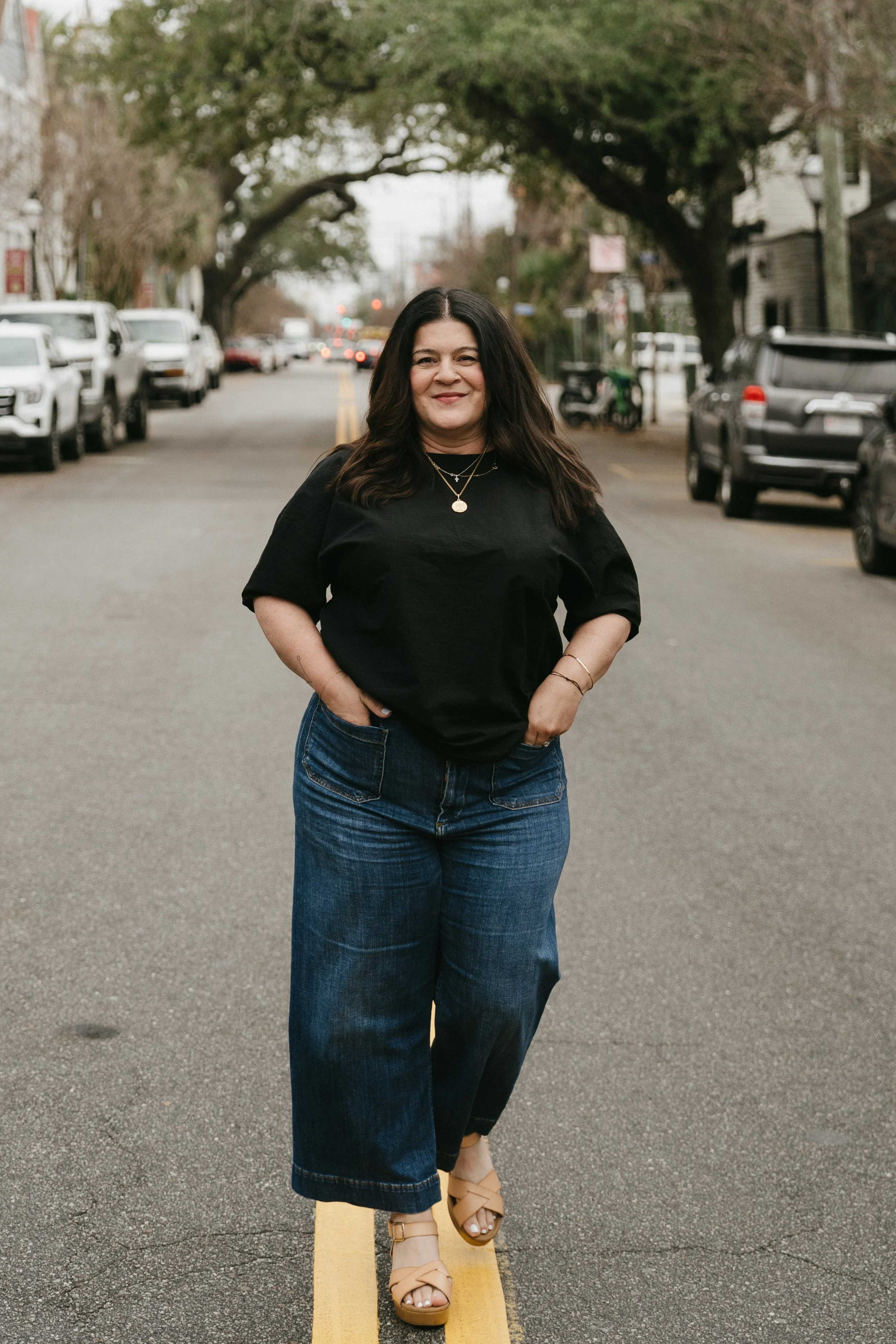 woman in black shirt and jeans looking at camera standing in street