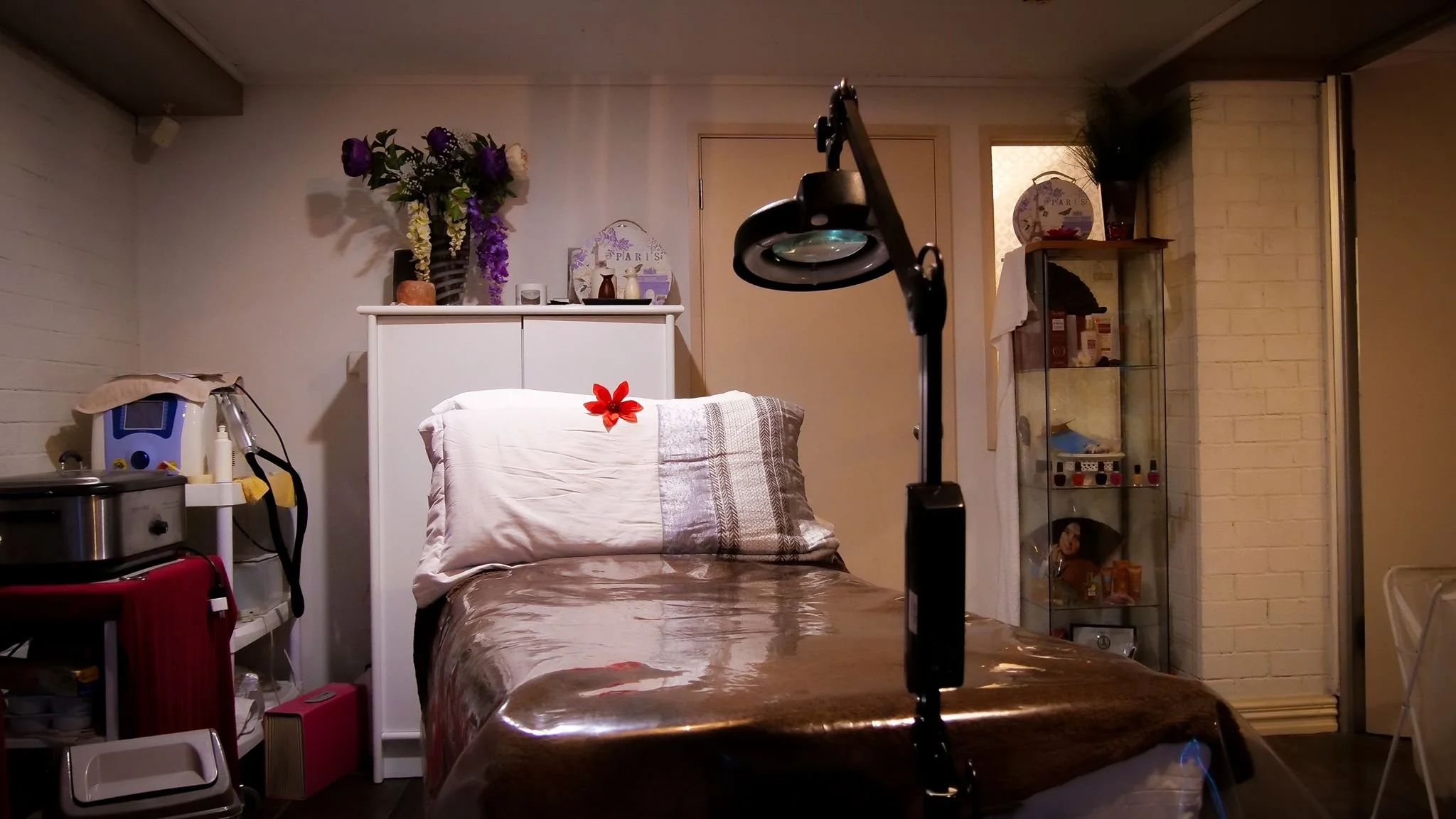 A hospital or medical treatment room with a bed, medical equipment, and decorative items on shelves and walls.