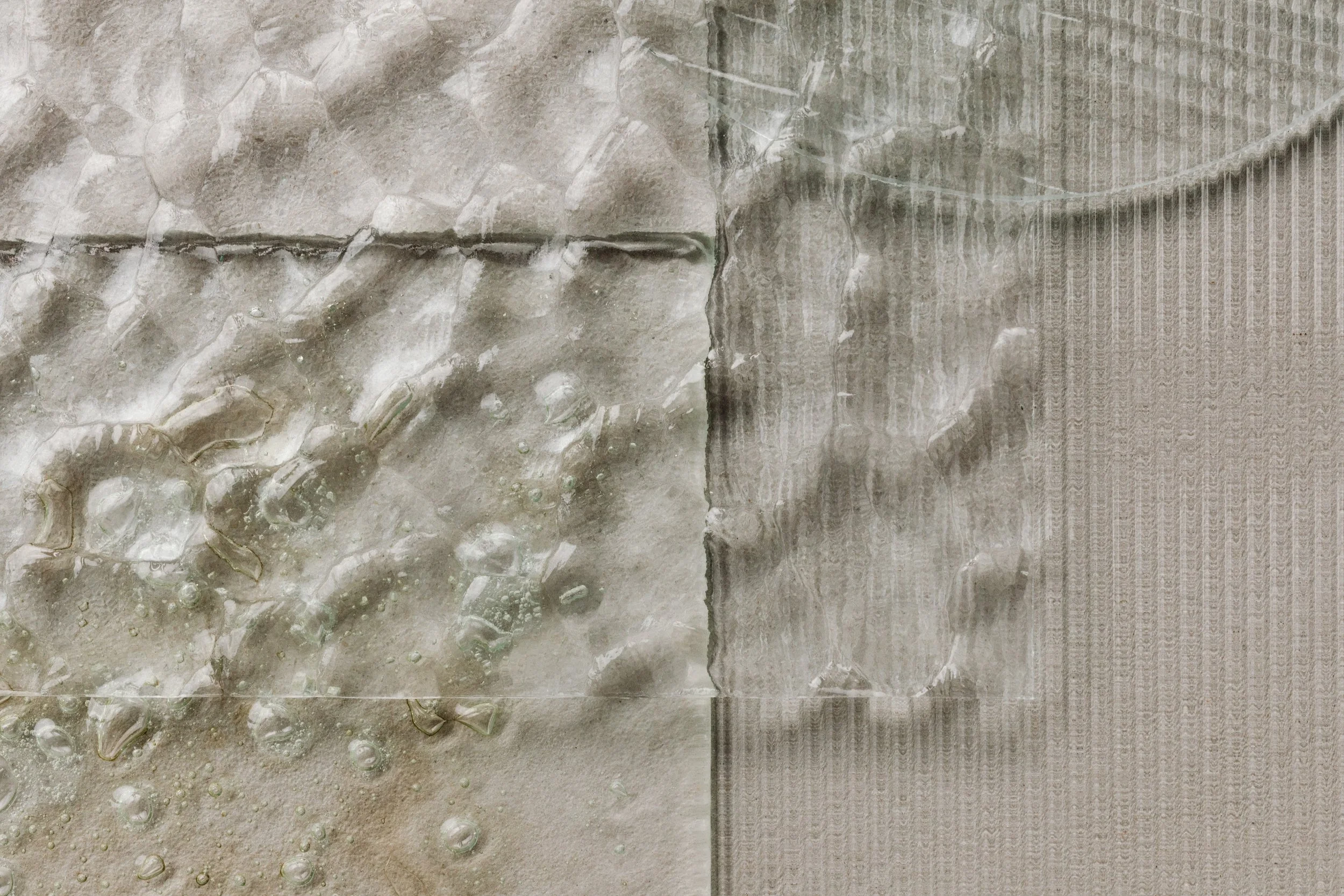 Close-up of transparent plastic bags with water droplets on beige and gray textured surfaces.