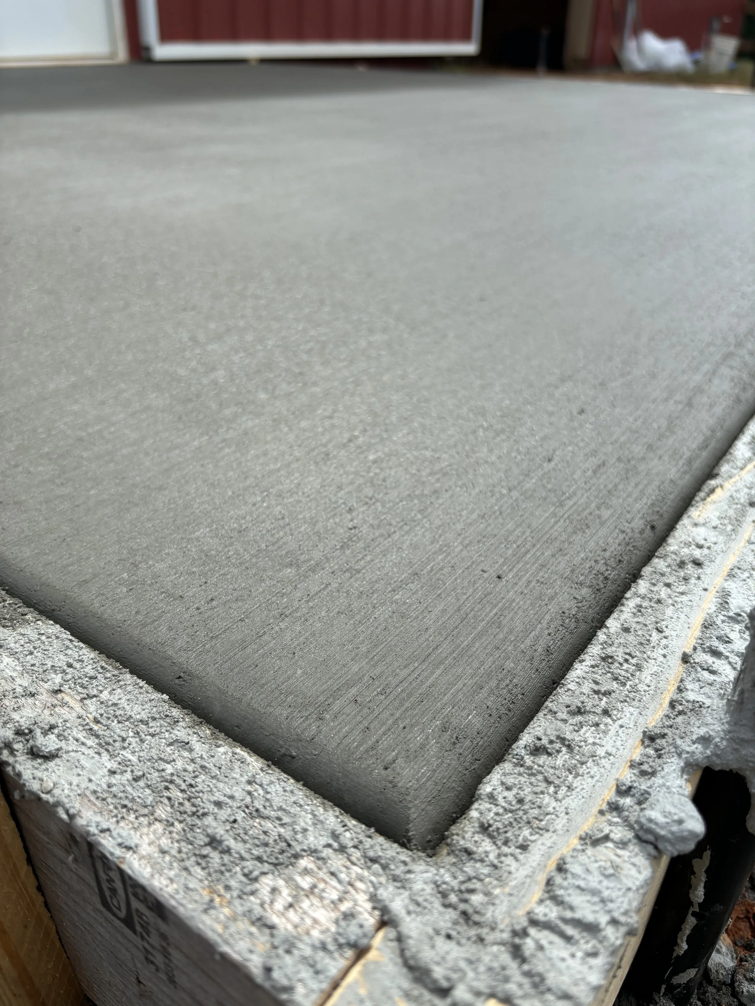 Freshly poured concrete slab with smooth finish and wooden framing edges.