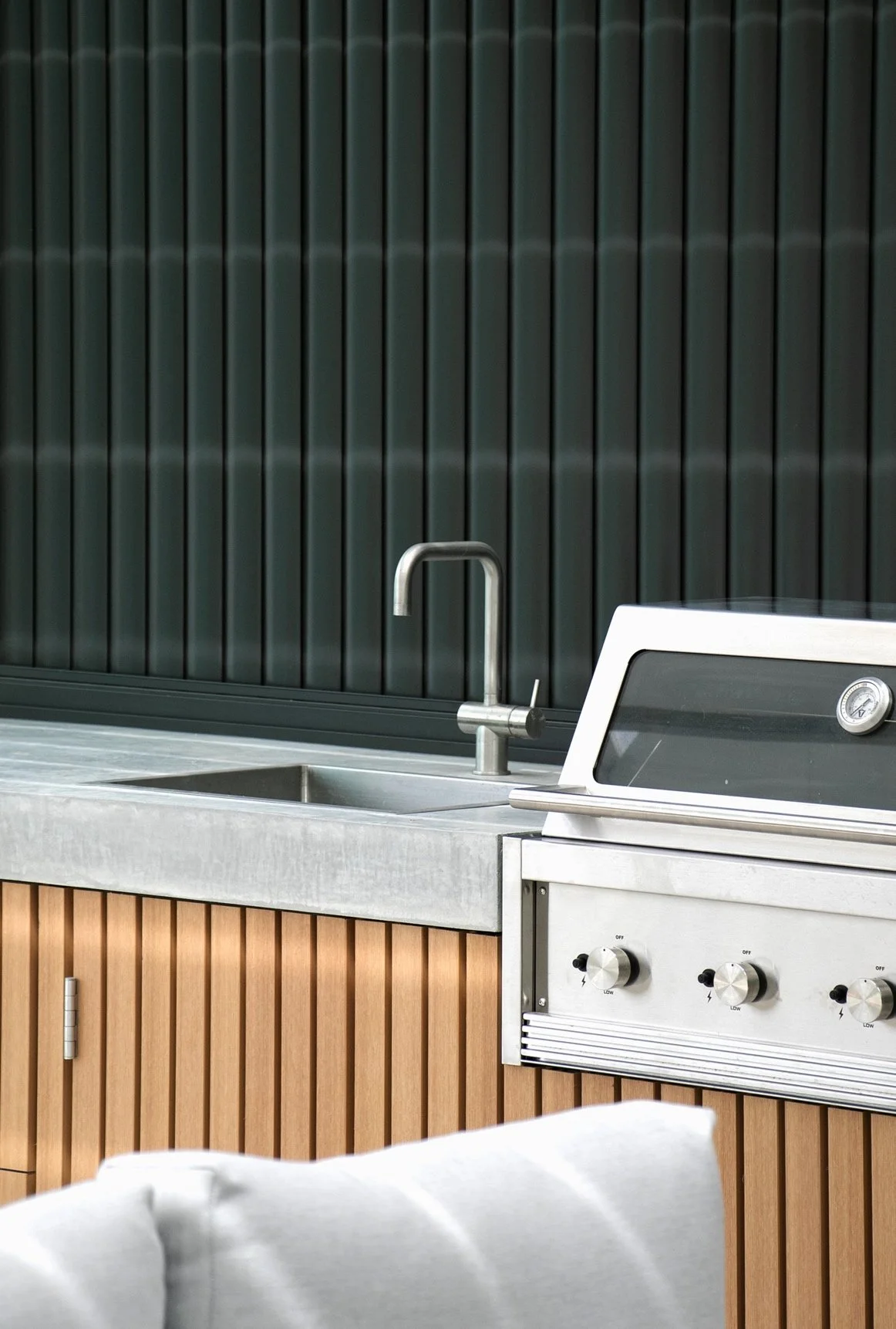 Outdoor kitchen with concrete benchtop, stainless steel BBQ and timber cabinetry by Sutherland Shire landscapers