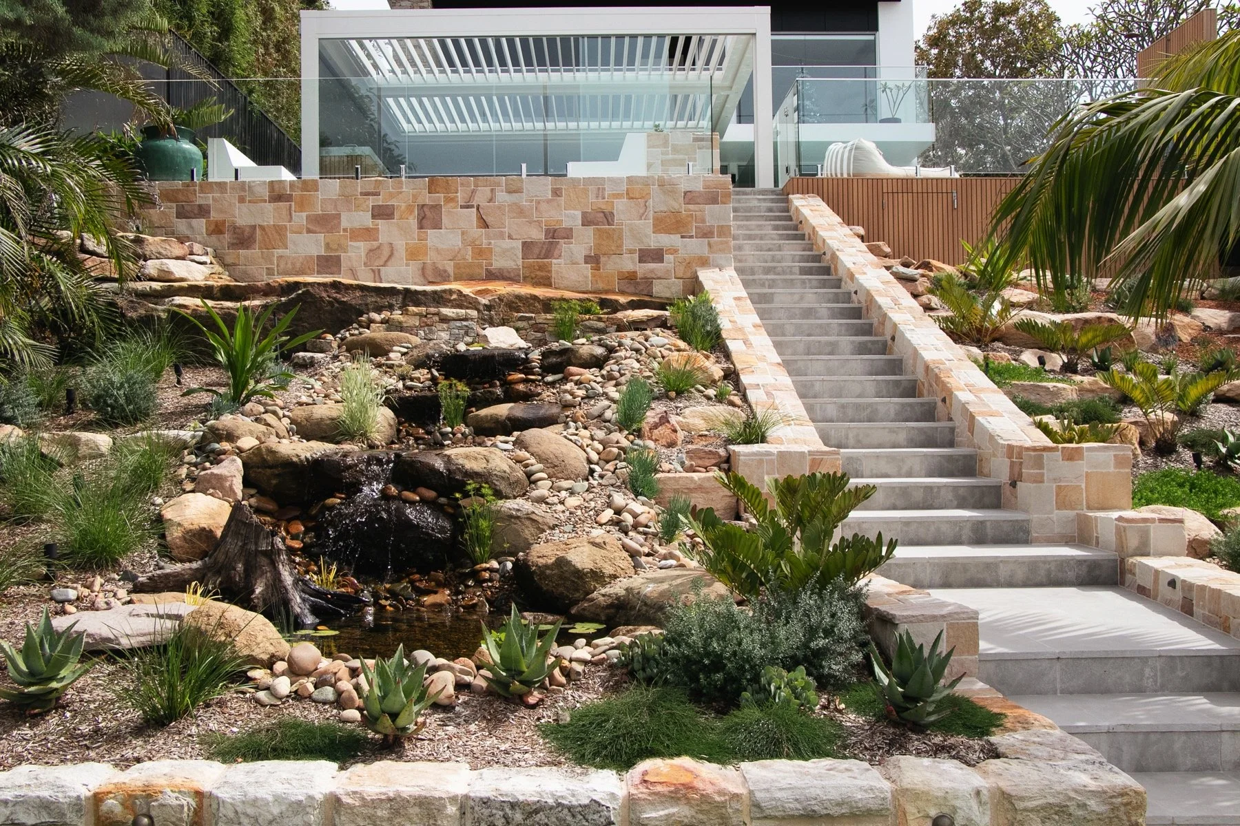 Waterfront luxury home with custom pool renovation and tiered sandstone landscaping in Burraneer Sutherland Shire