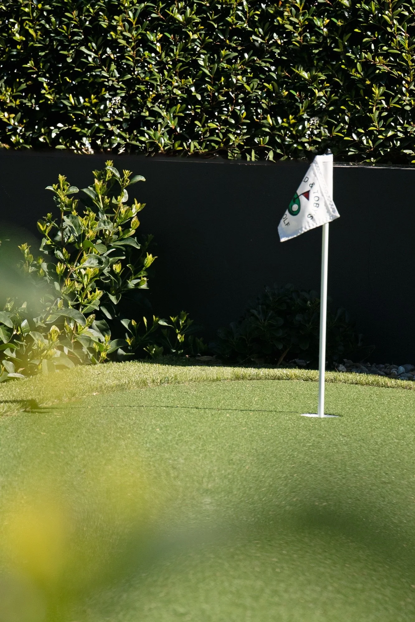 Putting green flag against a lush hedge in a Yowie Bay front yard