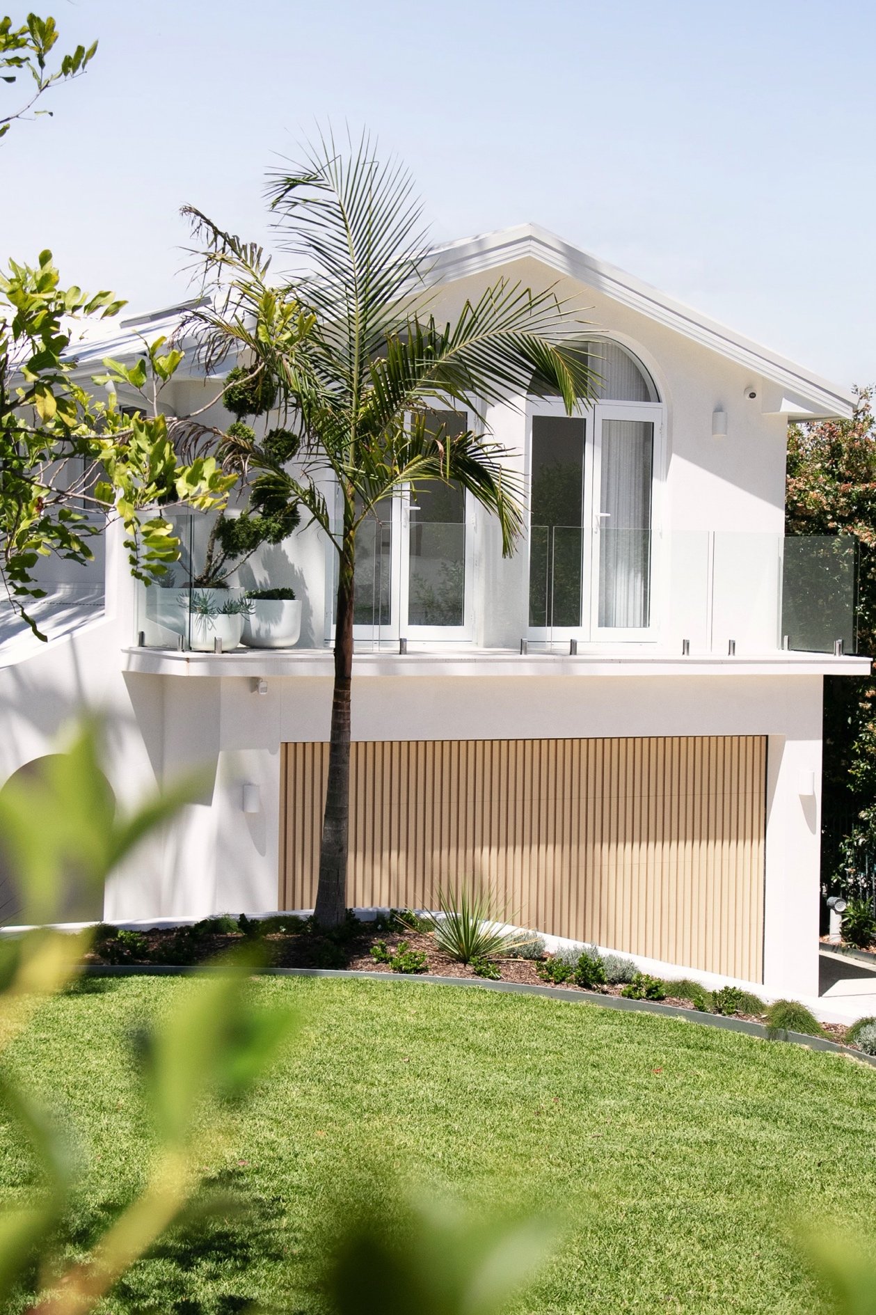 Side view of landscaped space in Sutherland Shire with a newly renovated home, palm trees, new lawn and a modern plant palette that has been professionally installed