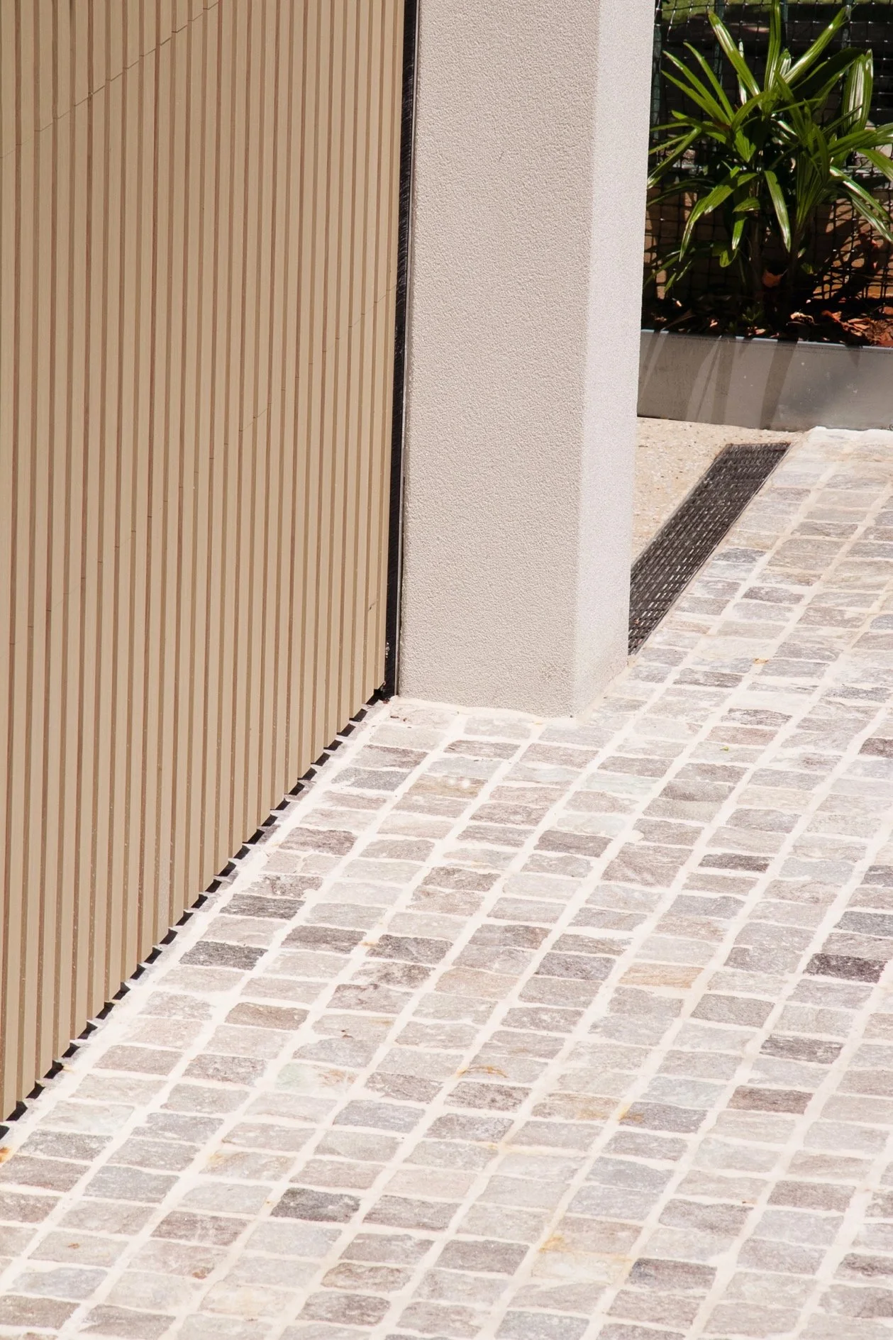 Close detail of cobblestone paving meeting the vertical timber garage door, part of the crafted finishes in this Port Hacking outdoor transformation.