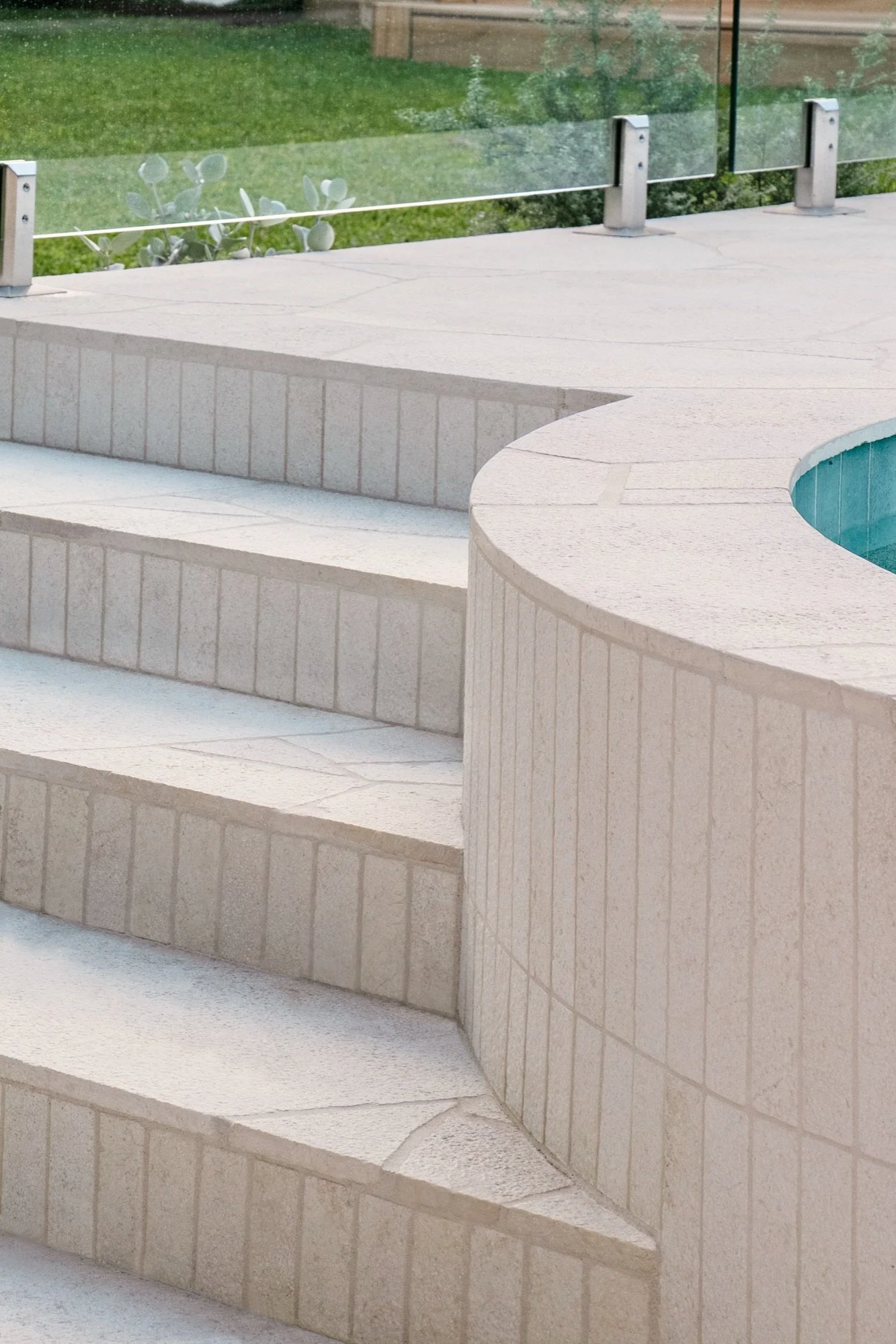 Curved pool wall and stone steps with vertical tile detail in a Chifley backyard