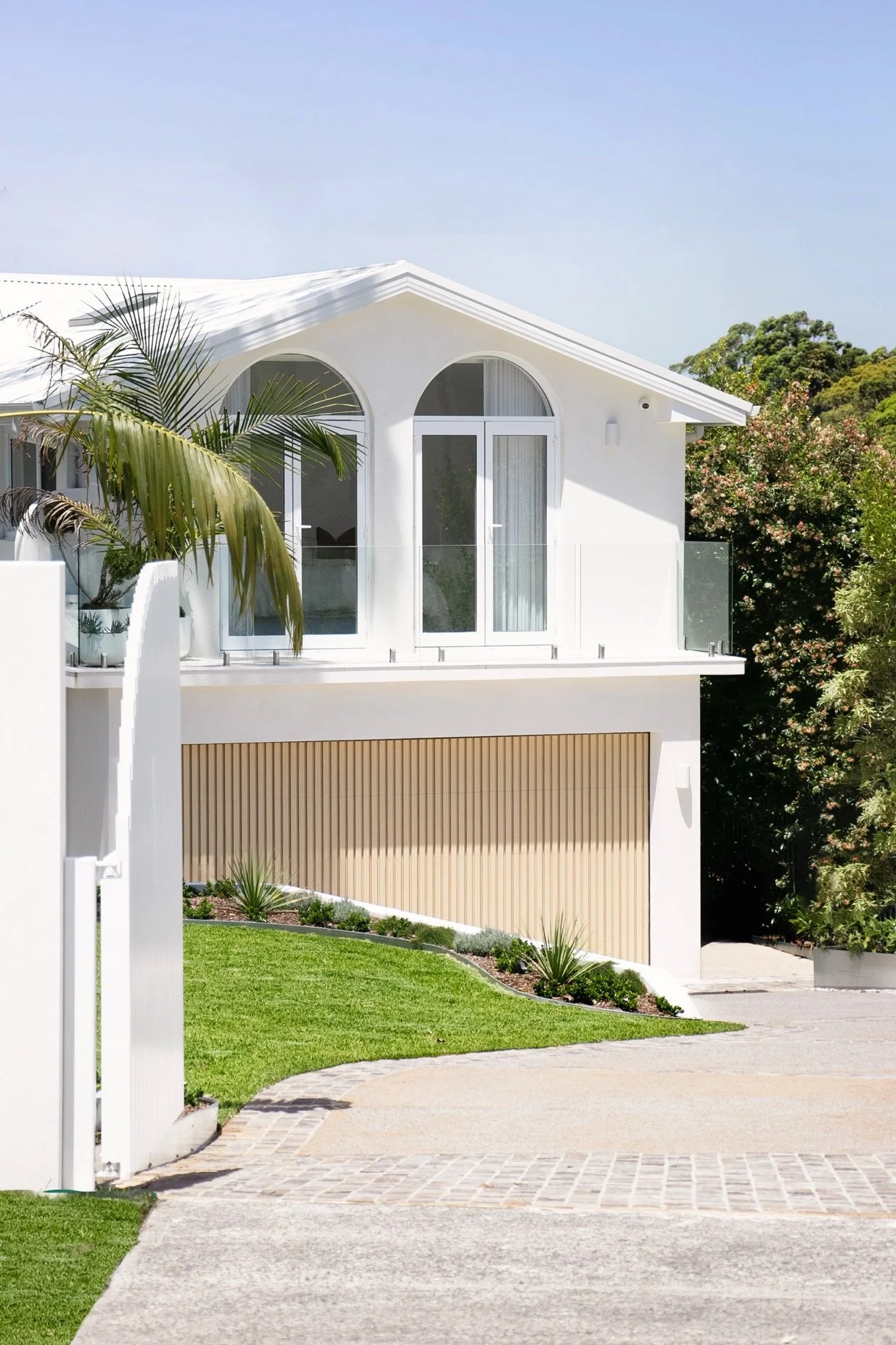 View from outside the professionaly landscaped home with concrete and cobblestone driveway leading to new home, level lawns, new gardens, palm trees and custom electric gate