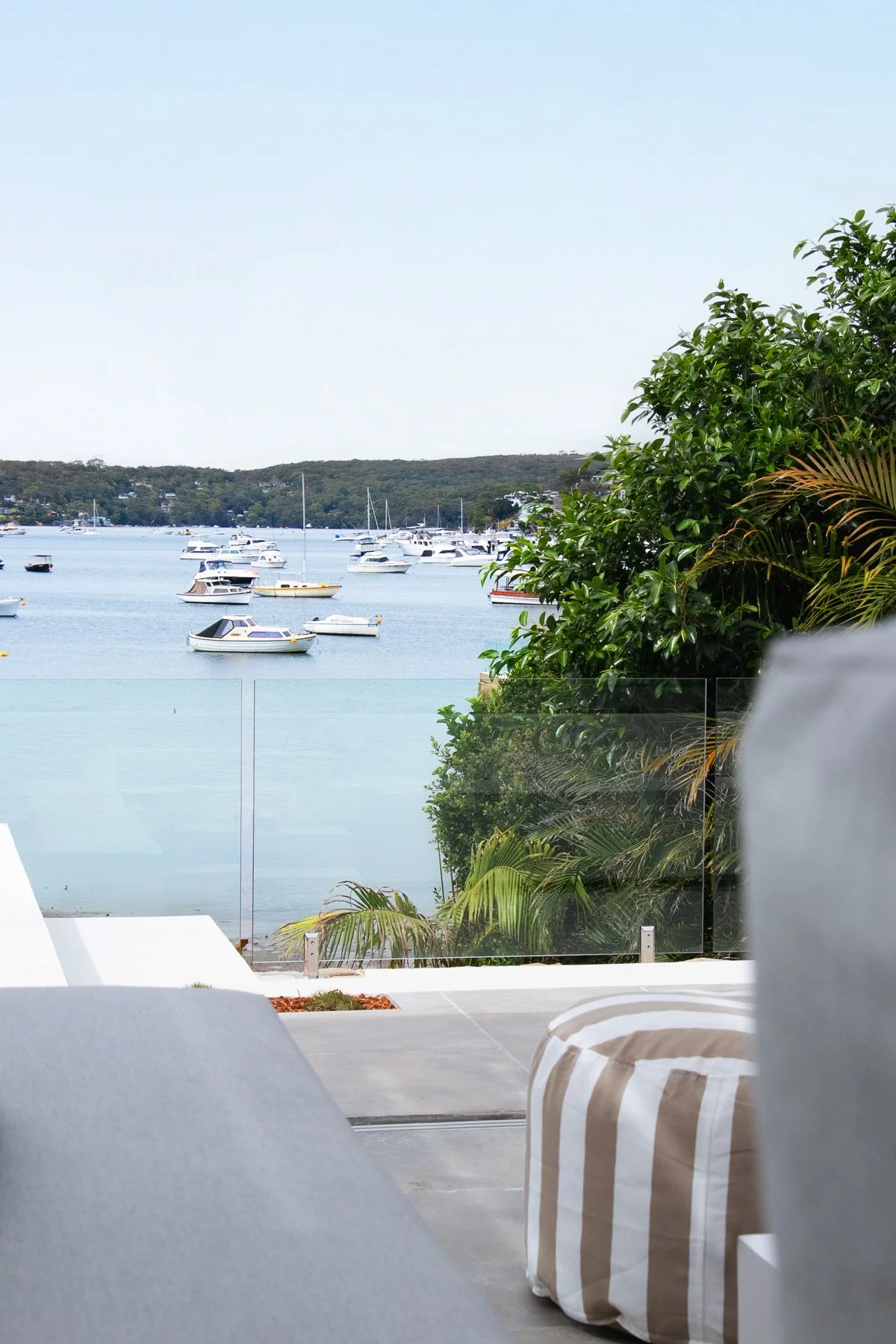 Waterfront outdoor entertaining area with glass balustrade and pool, luxury landscape design Sydney