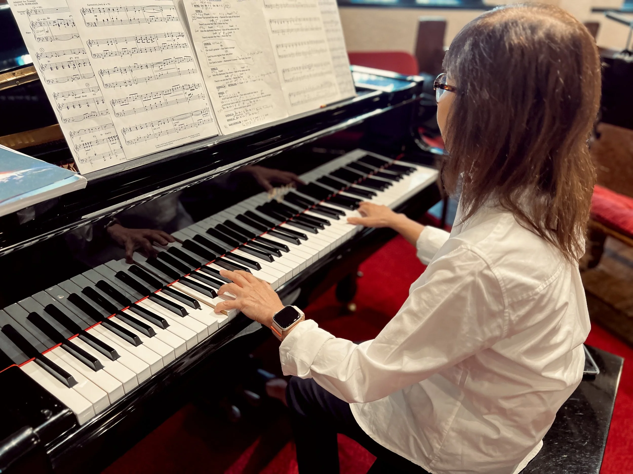 Person playing a grand piano with sheet music on the music stand.