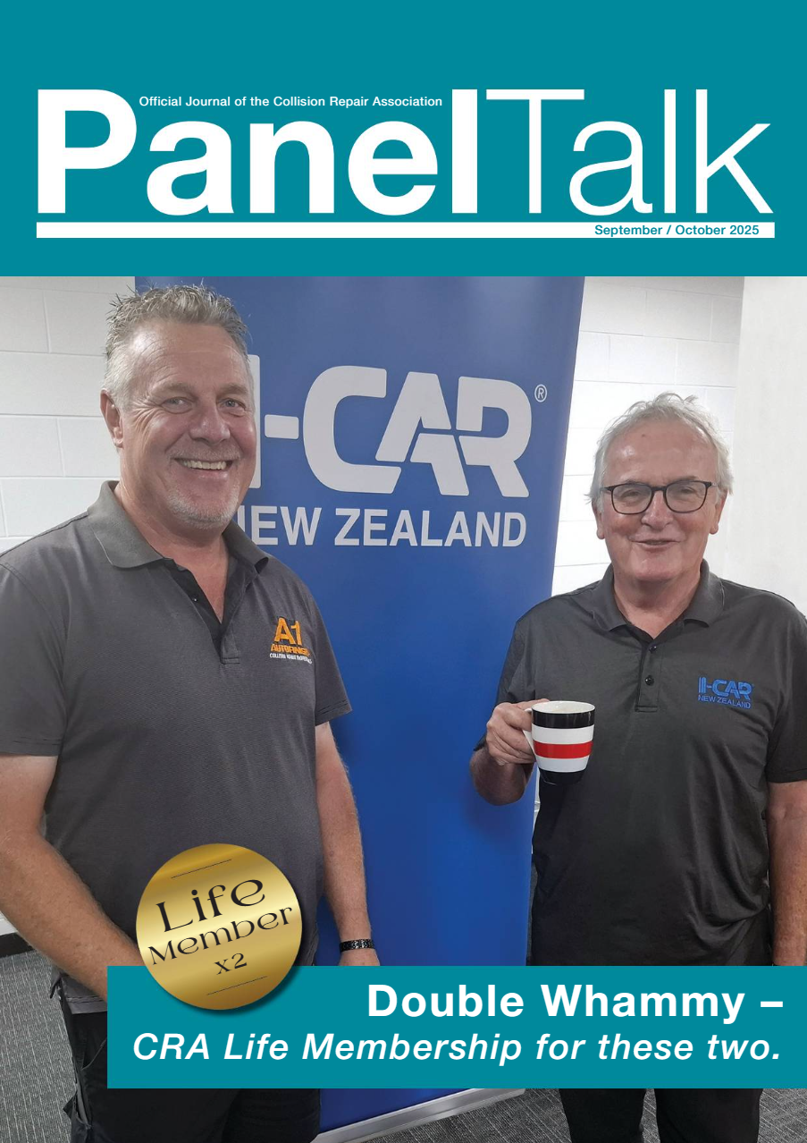 Two men standing in front of a blue CRA New Zealand banner, smiling and holding a mug, at a professional event or conference, with the magazine cover overlaying the image