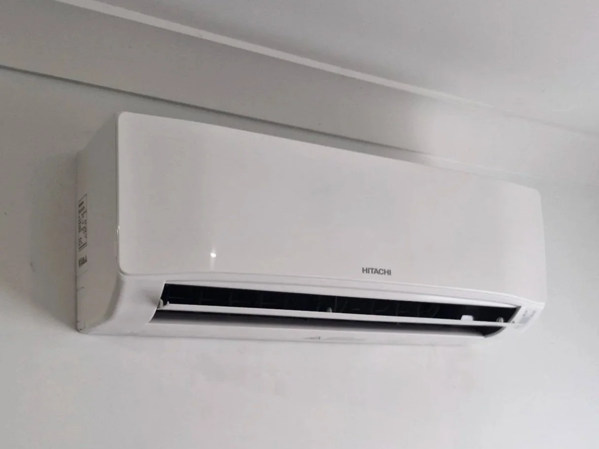 A white Hitachi wall-mounted air conditioner unit installed near the ceiling.