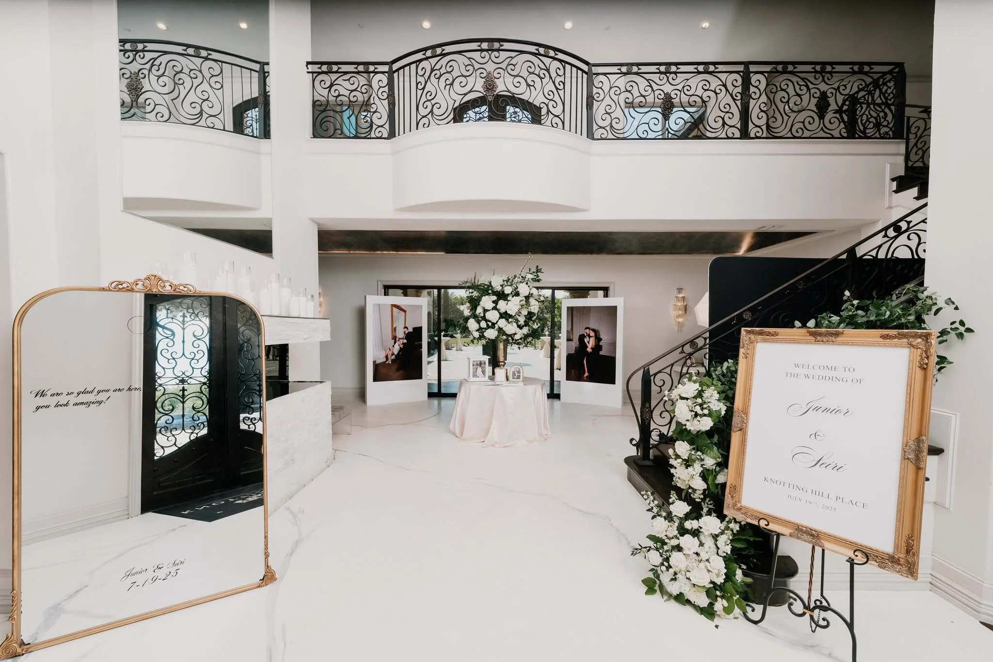 Elegant wedding reception area with white decor, floral arrangements, and welcoming signage for Junior and Sevi at Knotting Hill Place.