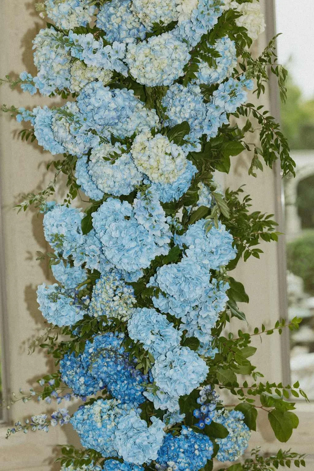 A floral arrangement with light blue and white hydrangea flowers and green leaves.