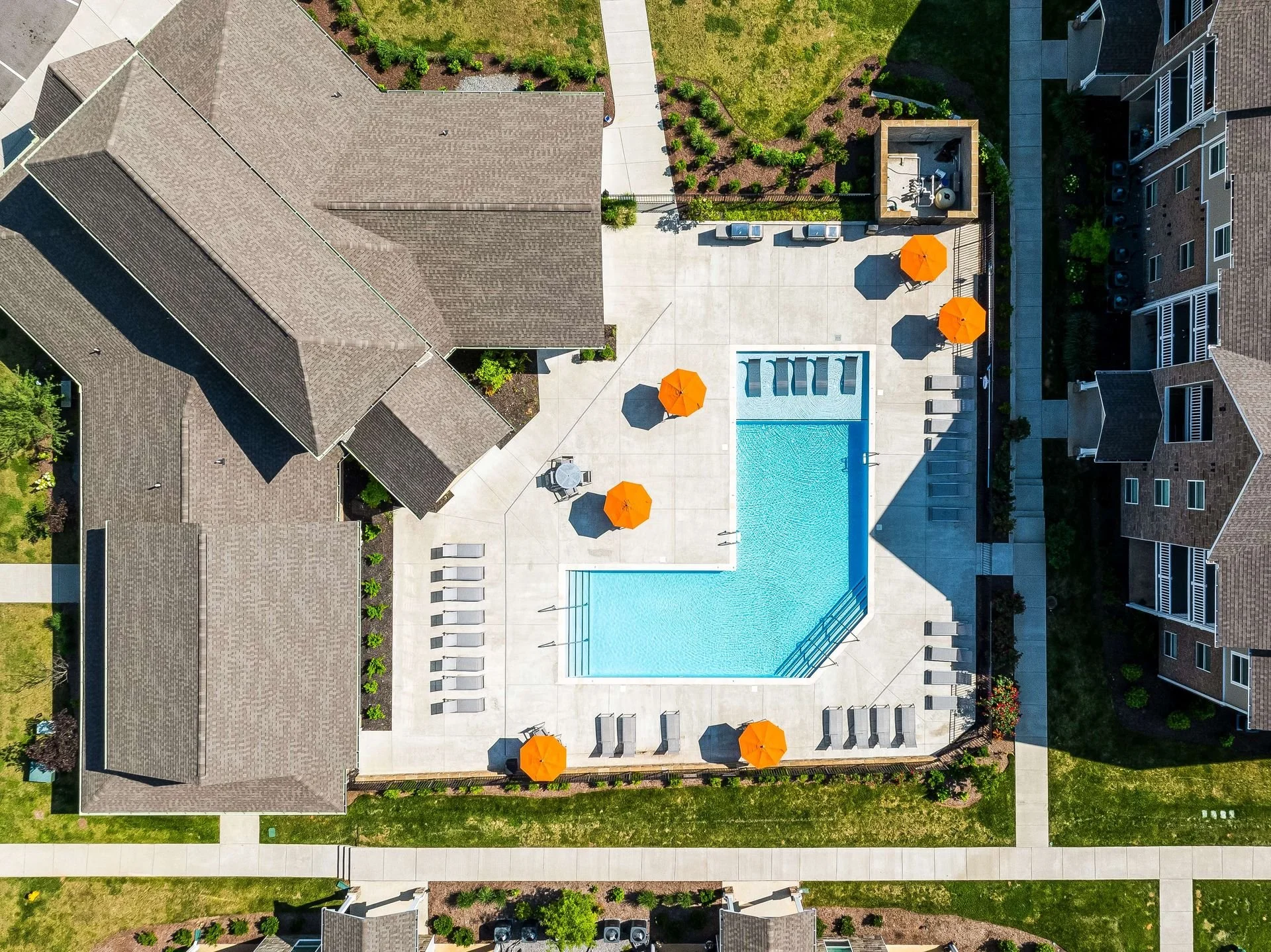 Modern conference room with a white wall displaying the words 'RR LIVING' in large black letters and a stylized 'RR' logo in a black square. There are several gray office chairs around a beige conference table.