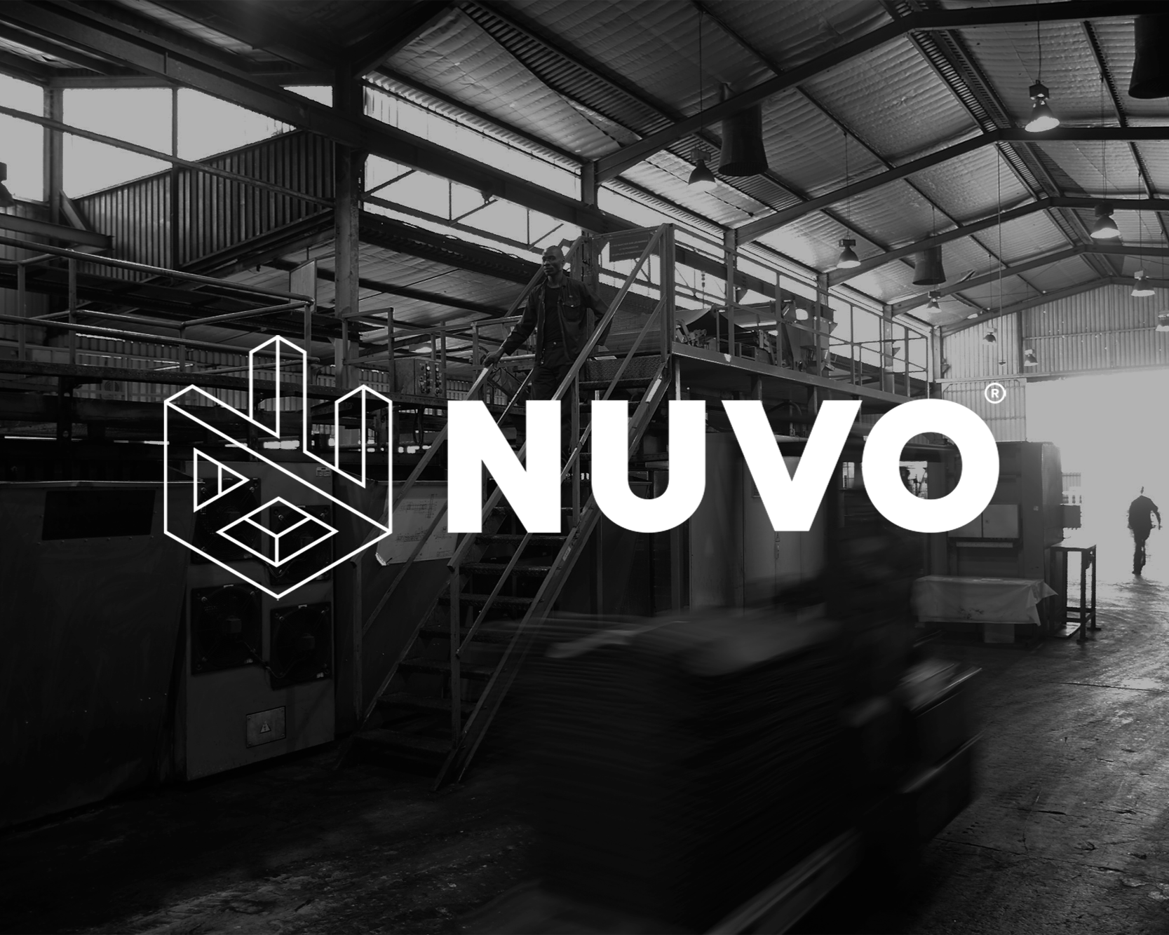 Inside a large industrial warehouse with metal roofing and lighting, people working on machinery, and the NUVO logo overlayed in white.