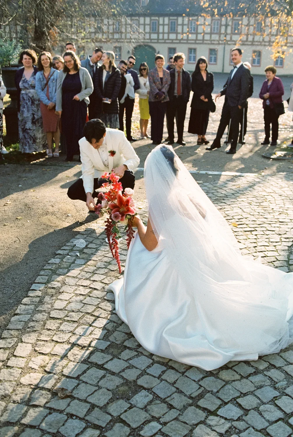 Documentary shot of a couple on their knees on cobblestones at Schloss Lübbenau, honest wedding photography.