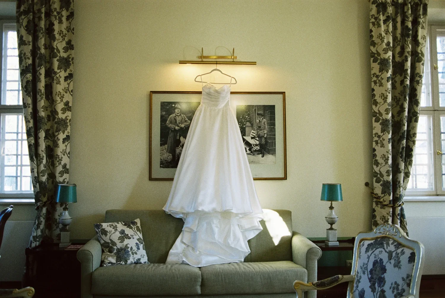 Minimalist wedding dress hanging above a sofa between vintage windows at Schloss Lübbenau.
