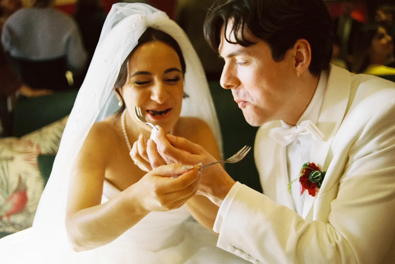 Close-up of the bride and groom feeding each other cake, real and emotional interaction captured on film.