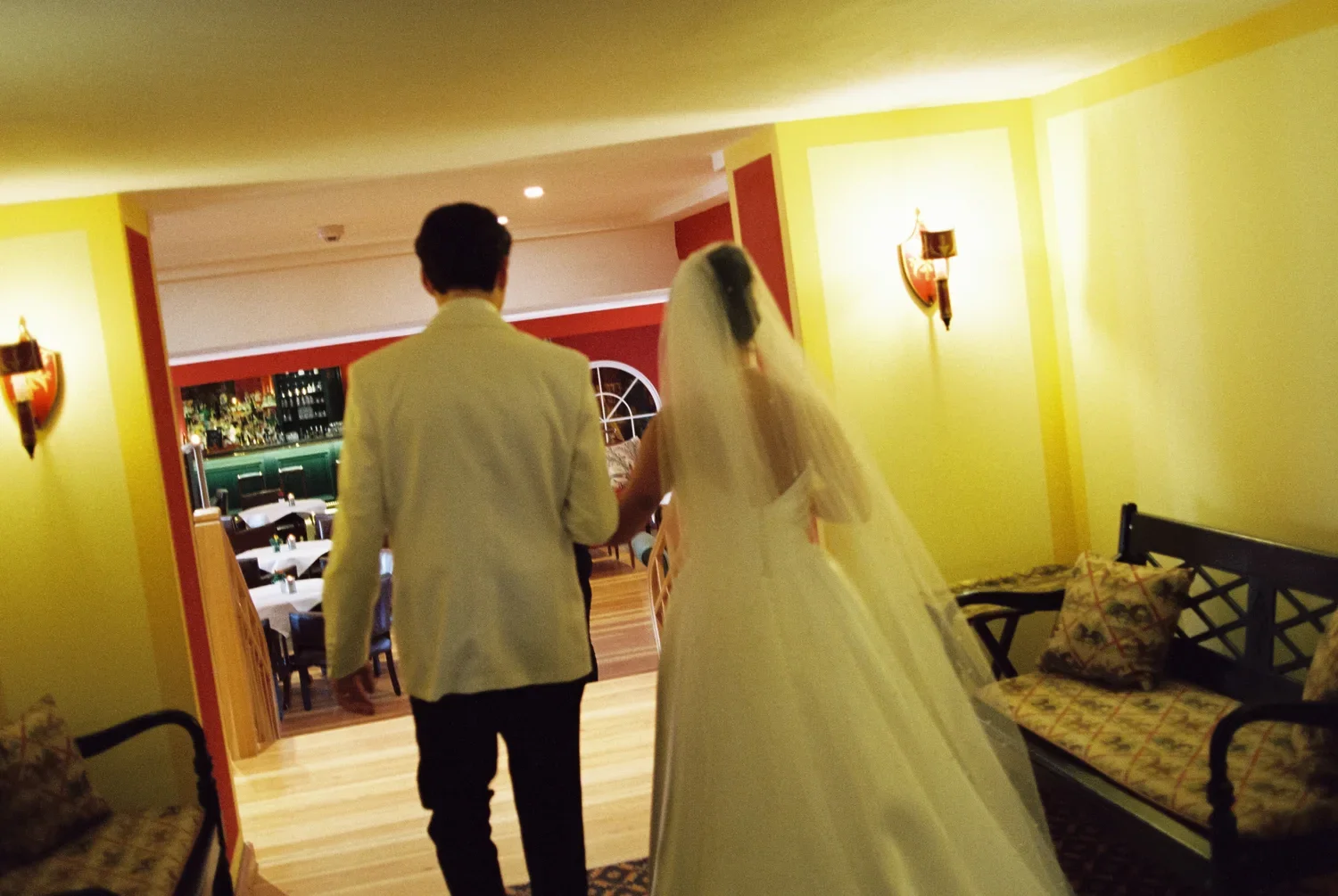 Intimate close-up of hands cutting a rustic wedding cake adorned with berries and figs, captured on grainy 35mm analog film at Schloss Lübbenau.