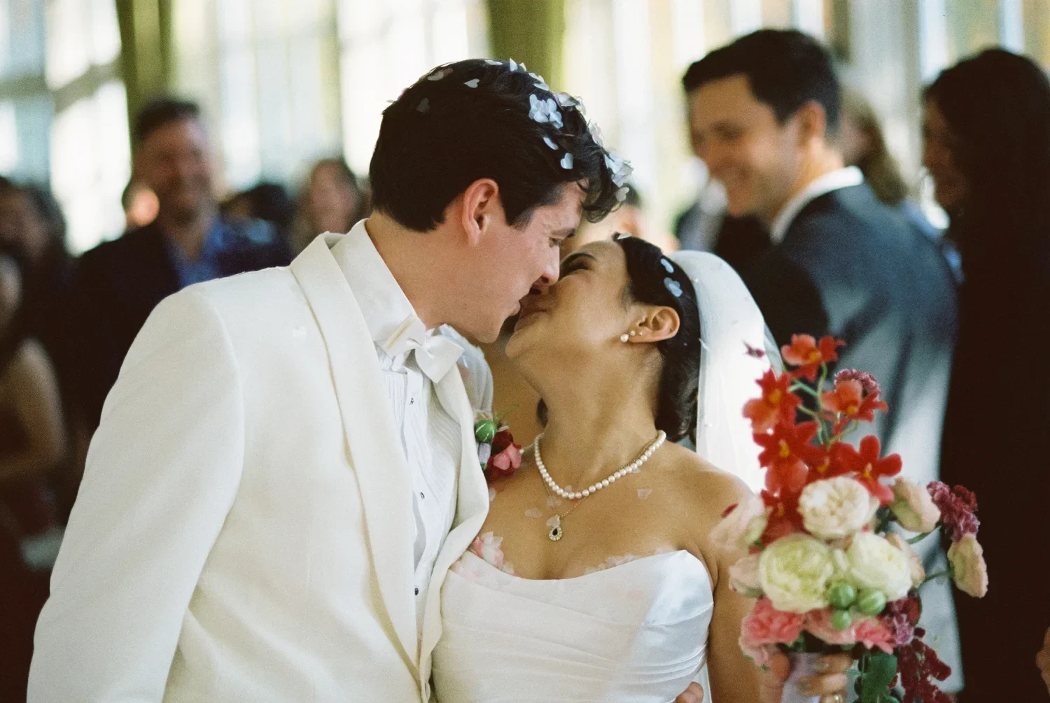 Close-up of a couple's kiss during the recessional with confetti, emotional analog photography.