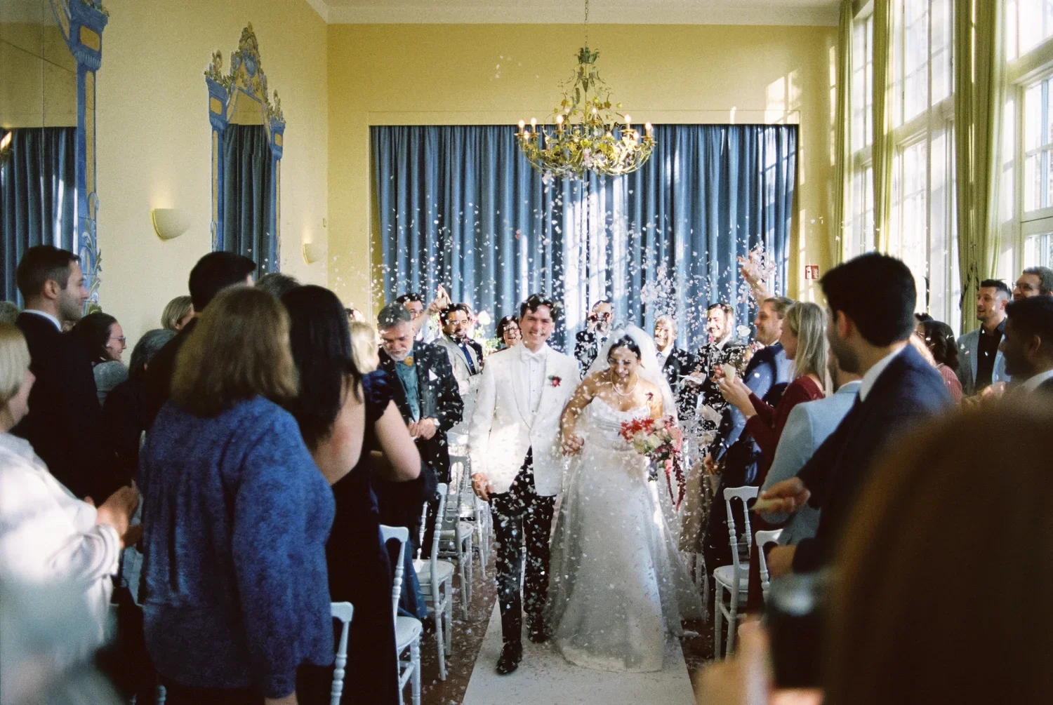 Couple walks through confetti at Schloss Lübbenau, high energy analog wedding photography.
