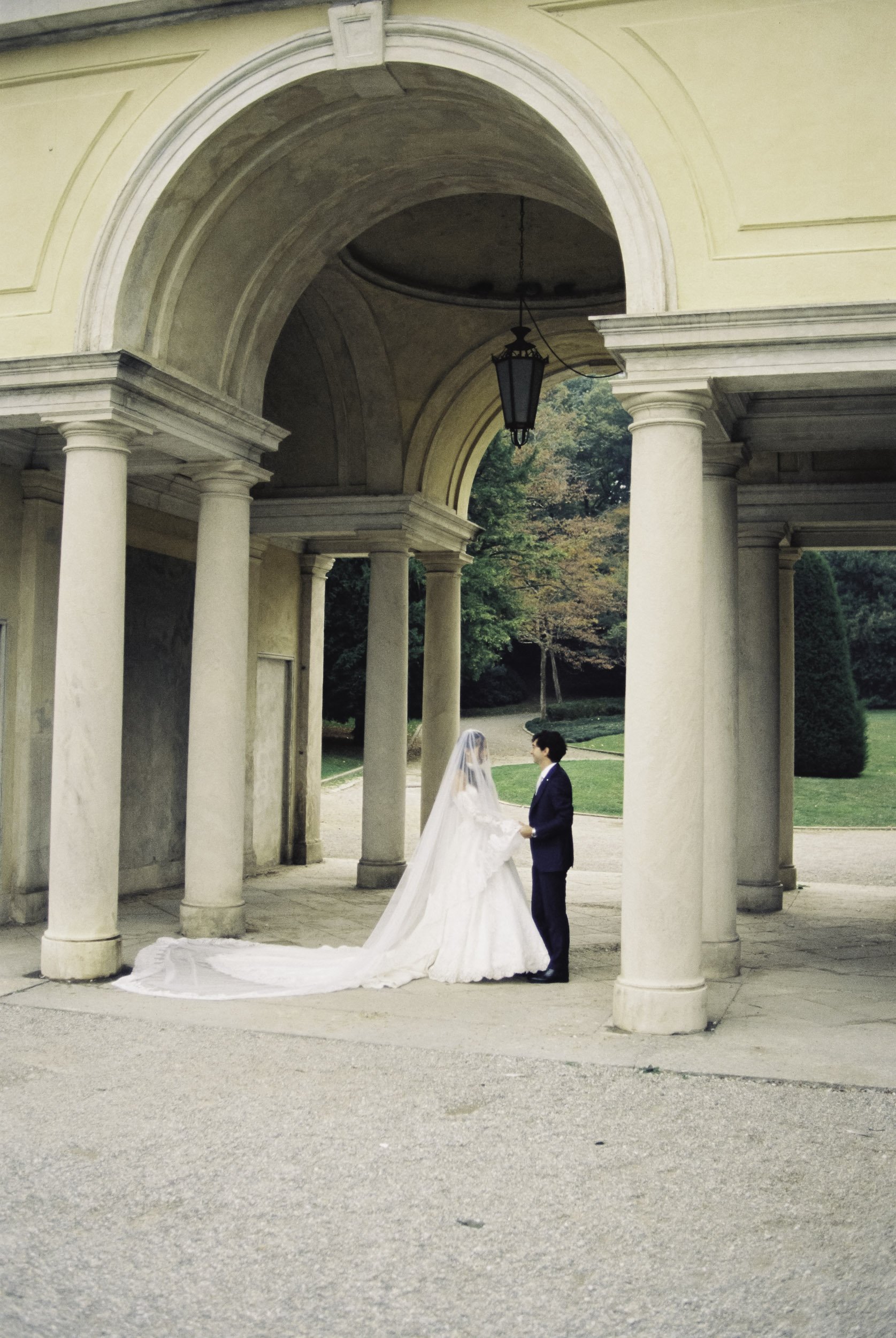 Editorial after-wedding session showing bride and groom under neoclassical stone arches at Lake Como, Italy.