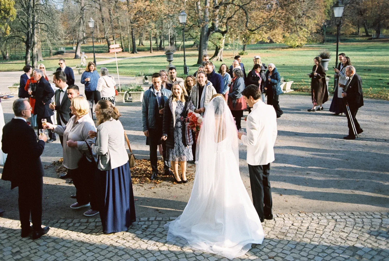 Atmospheric wide shot of a wedding reception in the park of Schloss Lübbenau, analog film aesthetic.