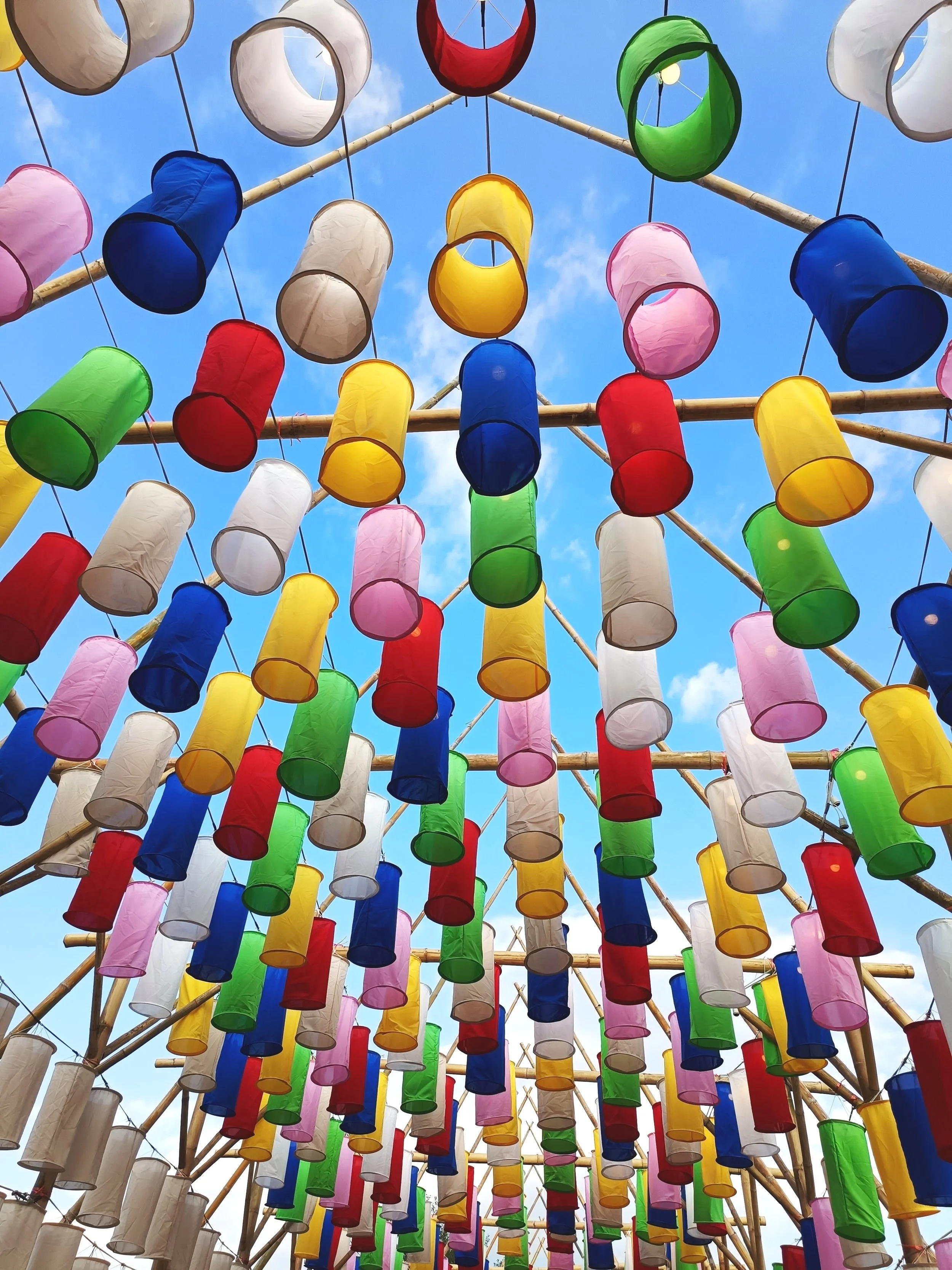Chiang Mai Yi Peng Lantern Festival with many colourful lanterns hanging at the top under a blue sky