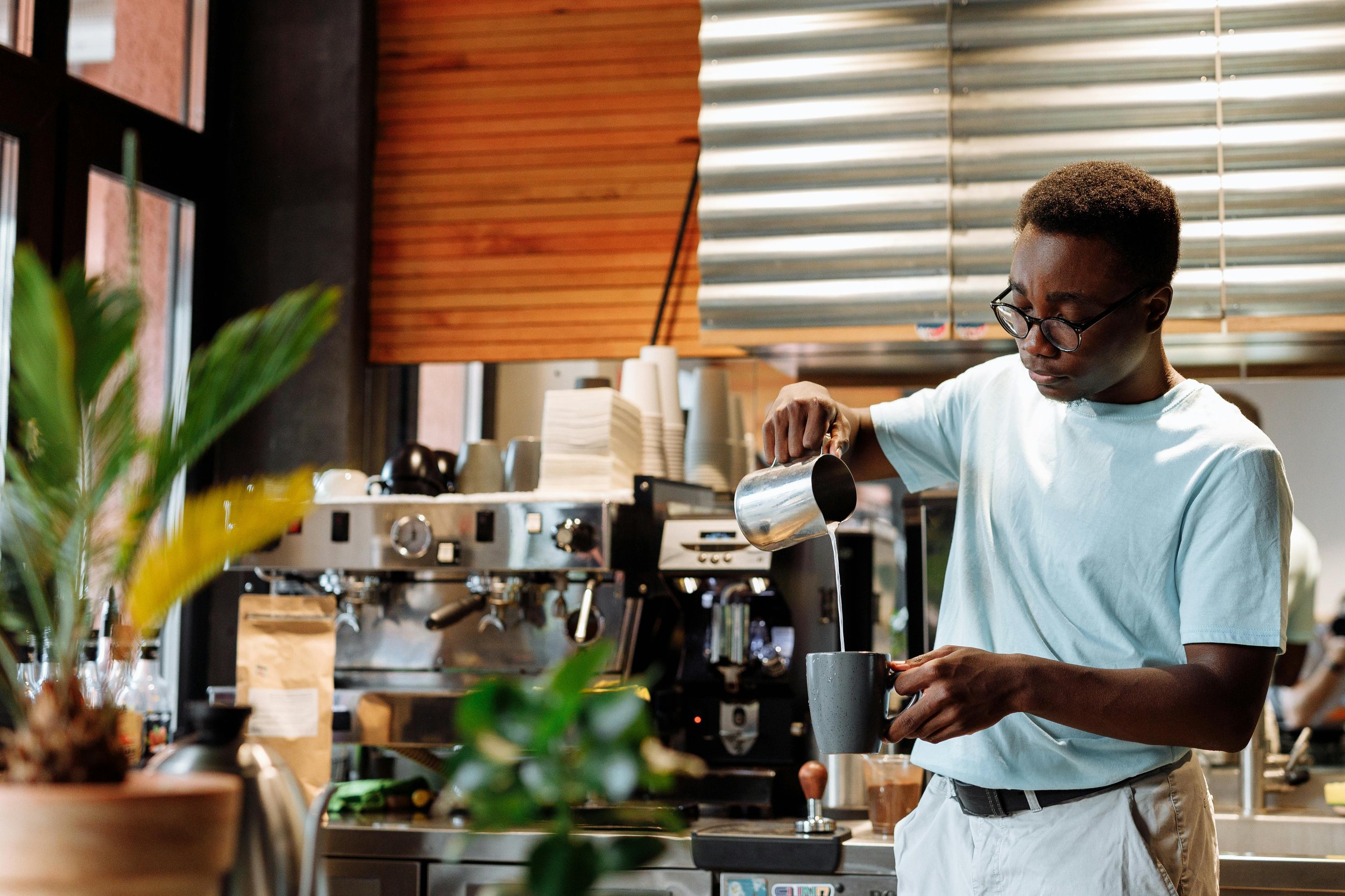Male barista pouring milk