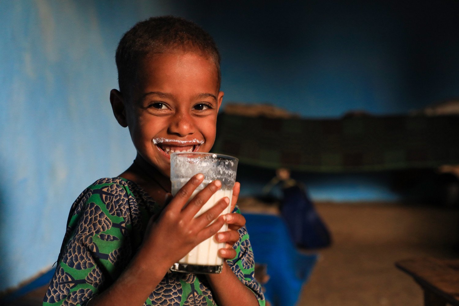 Girl drinking milk produced by the family cow.