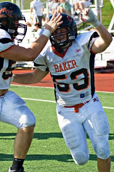 Football player wearing jersey number 53 celebrates with teammate on the field.