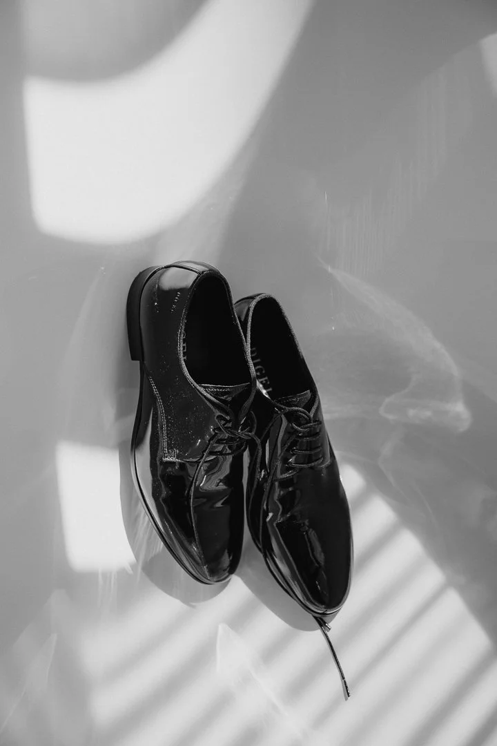 The groom's polished shoes in window light, black and white
