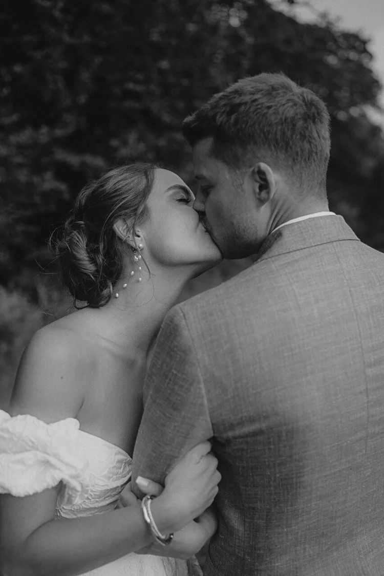 Brautpaar küsst sich bei ihrer Hochzeit auf Gut Ostenwalde, Schwarz-Weiß