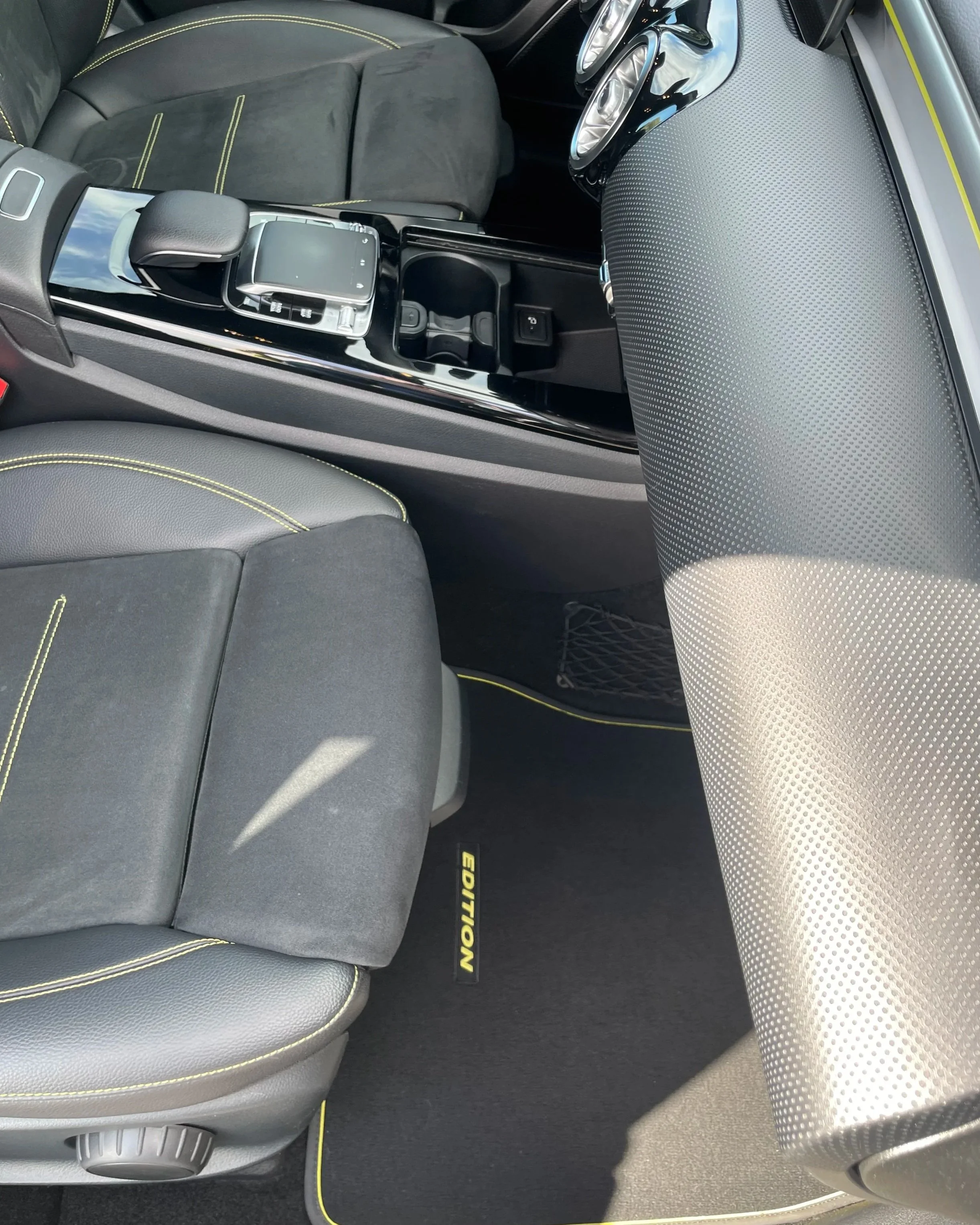 Intérieur de voiture, siège conducteur, console centrale avec commandes, volant, et tapis avec le mot 'EDITION'.