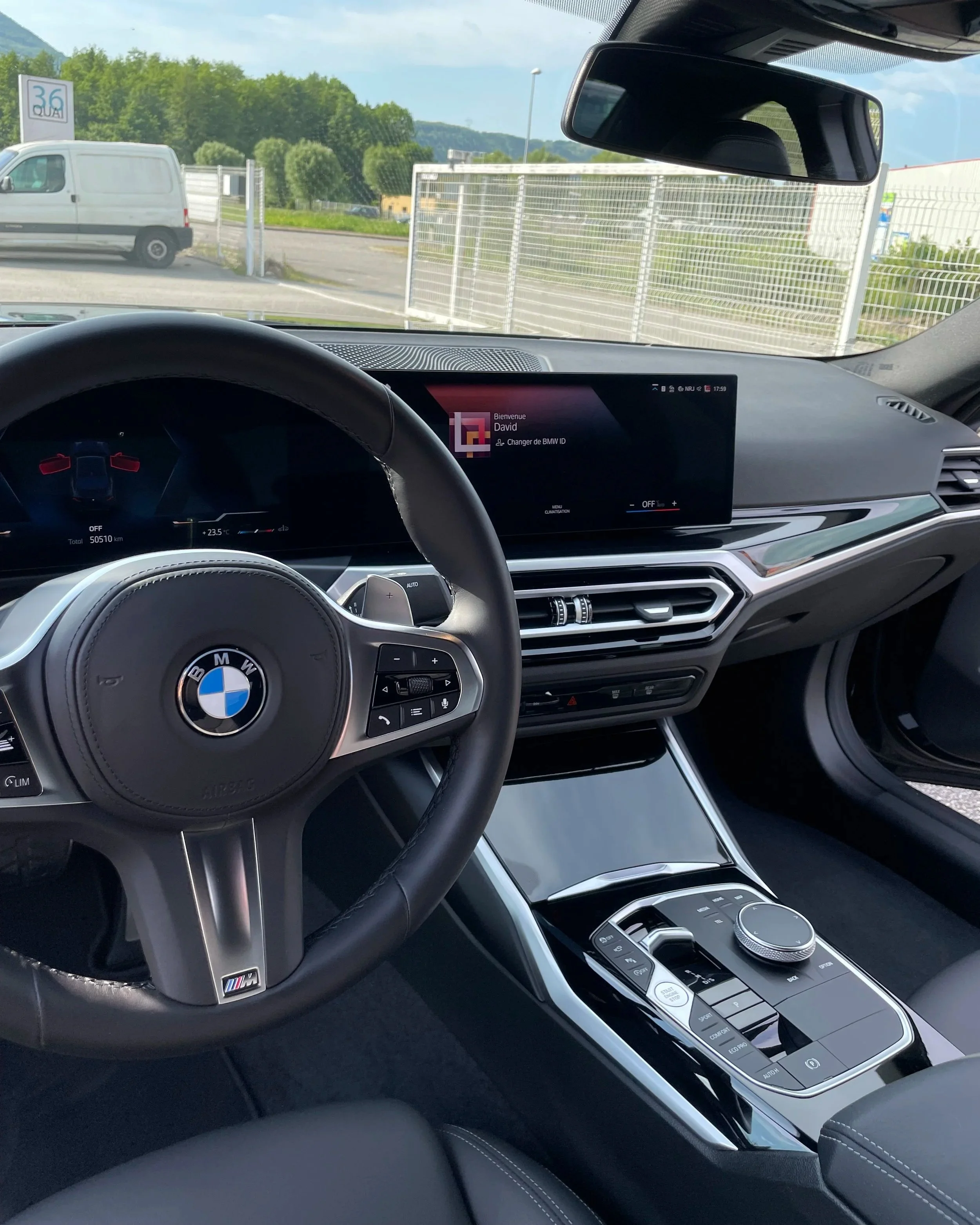 Intérieur d'une voiture BMW avec un tableau de bord numérique, un volant avec le logo BMW, et un centre de console moderne.